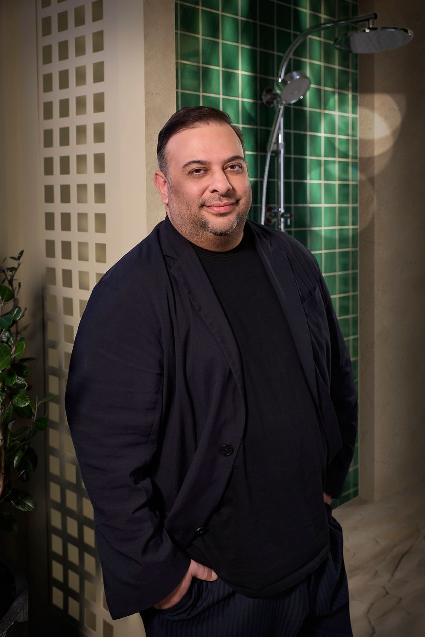 Designer Michael Hilal standing in front of a green tiled shower.