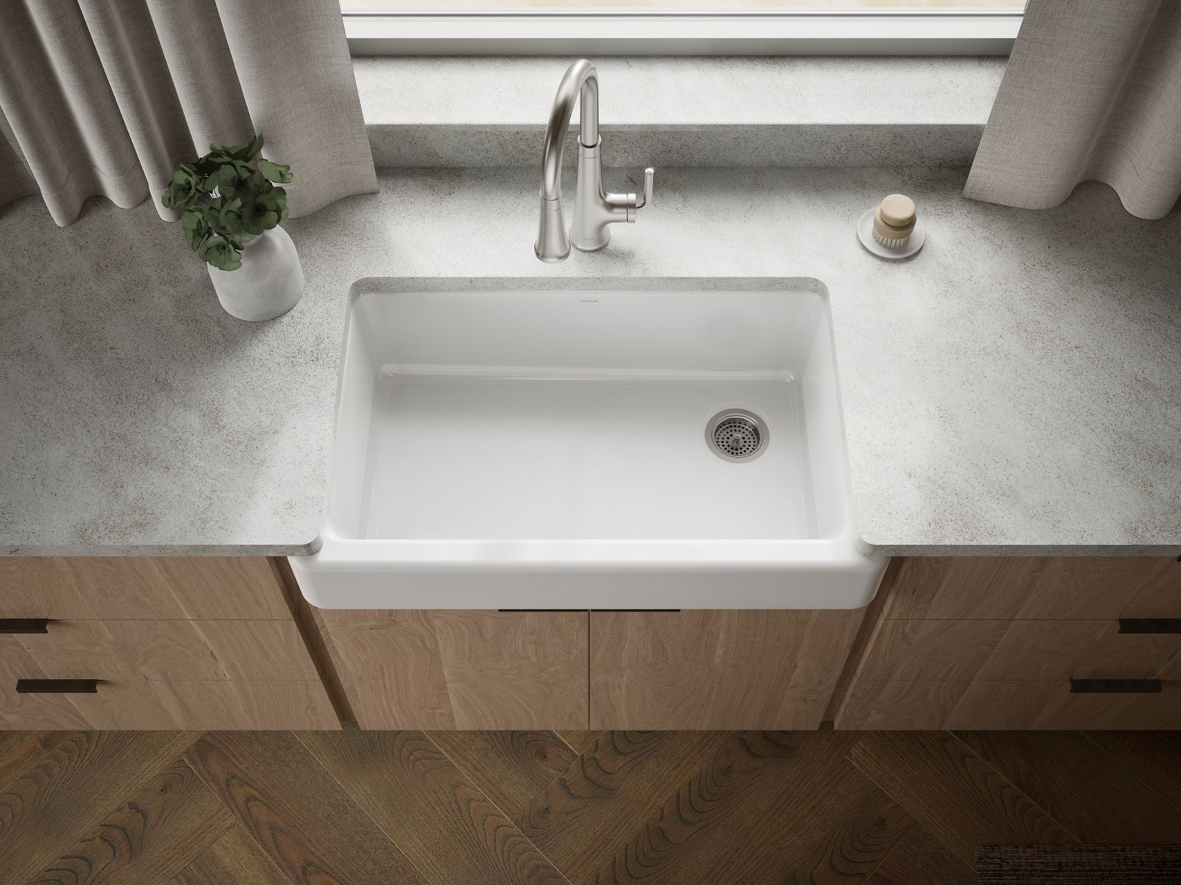 Farmhouse kitchen sink in a bright kitchen with white countertops and warm wood cabinets.