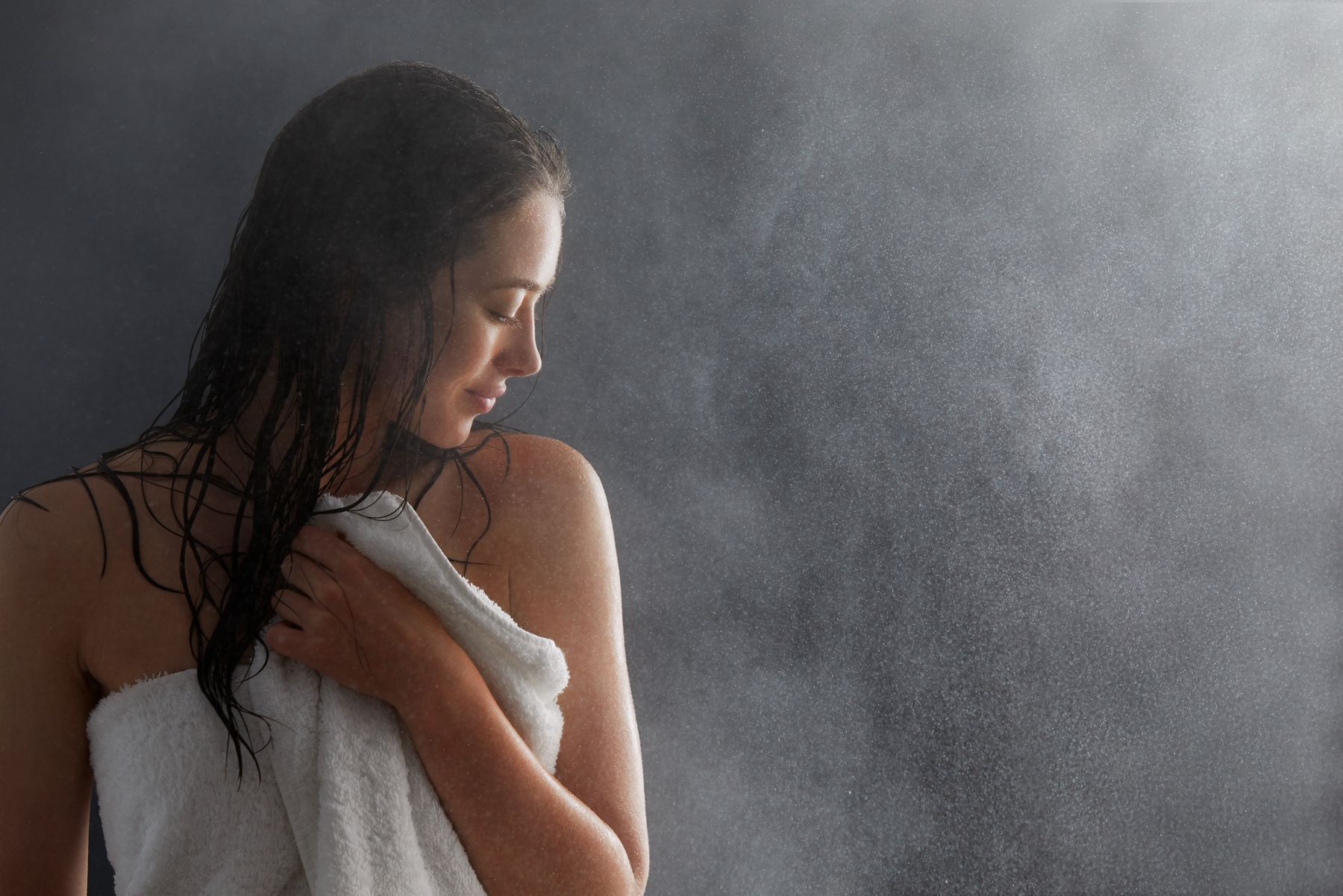 Close-up image of a woman in a towel, just exiting the showering, and looking over her shoulder at her soft skin.
