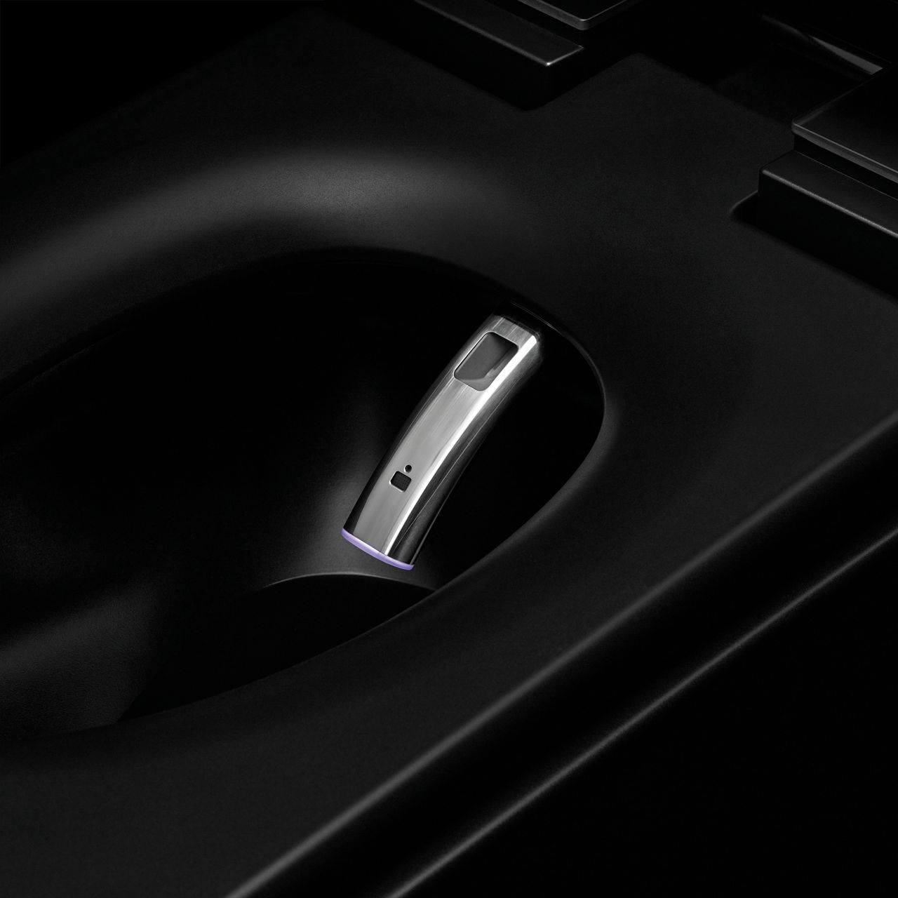 A stainless steel bidet wand extending into the interior of a black smart toilet.