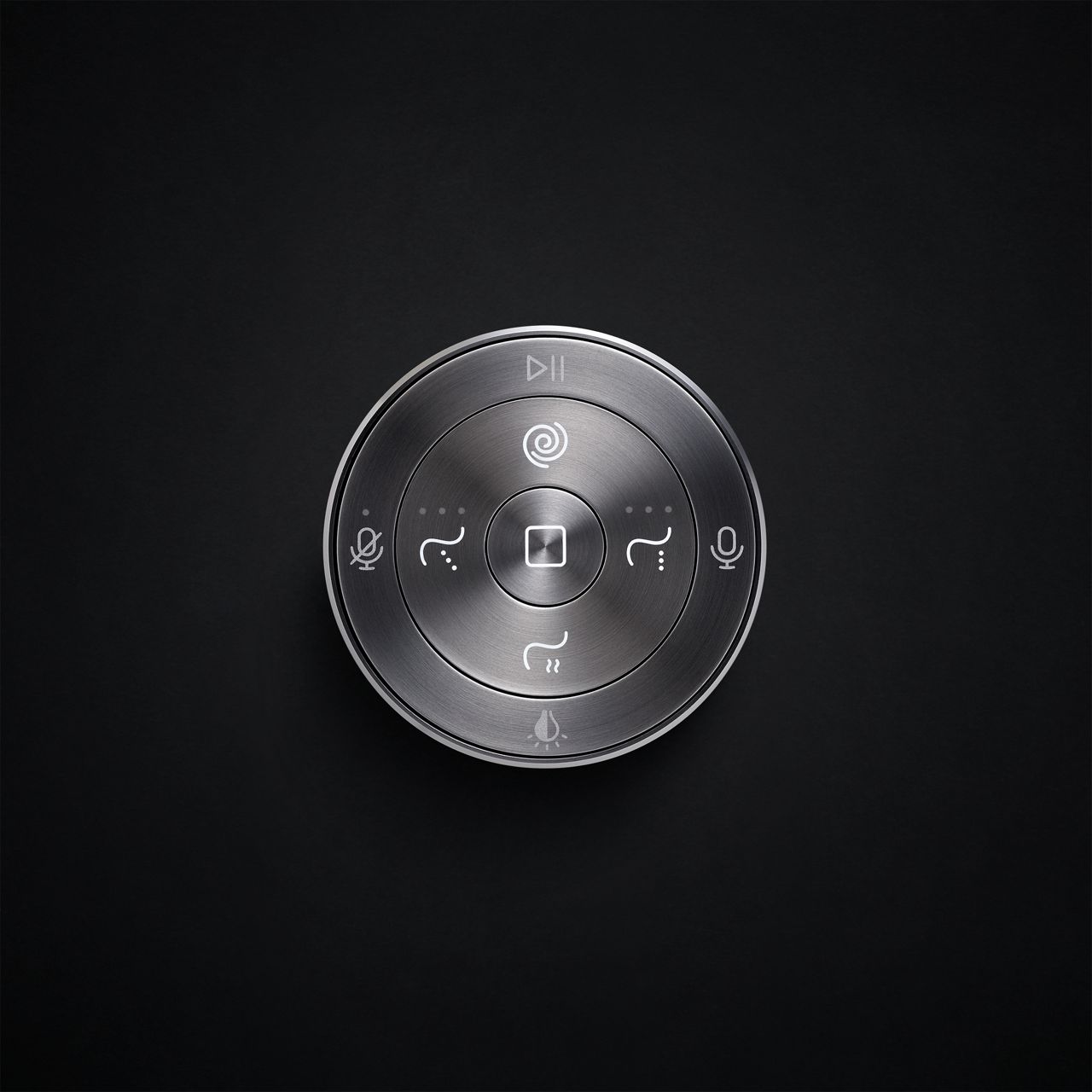 A round gray metallic remote control for a smart toilet mounted on a black wall.