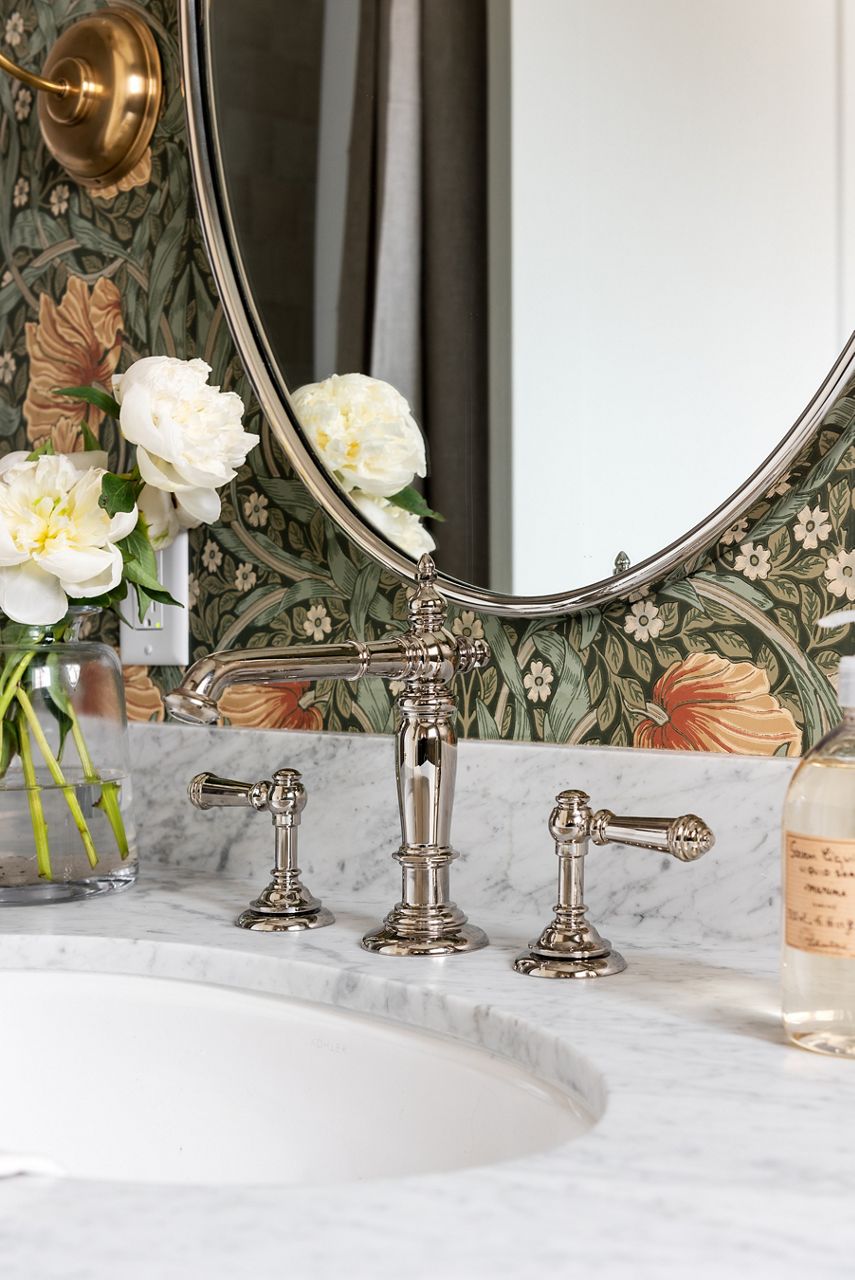 Widespread chrome faucet with separate spout and handles on a marble countertop.
