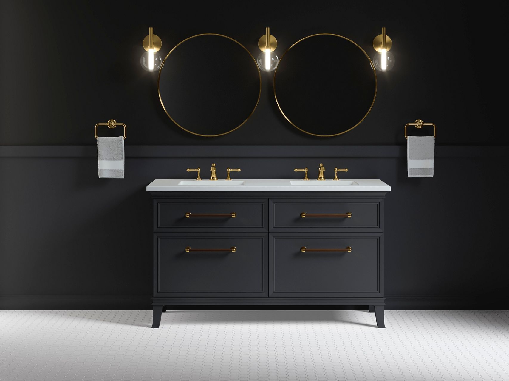 Une salle de bain sombre et apaisante avec un plancher en carrelage blanc, un meuble-lavabo double bleu marine avec un plan blanc et des robinets déployés en laiton contre un mur bleu marine, flanqué de serviettes blanches sur des anneaux porte-serviette, avec deux miroirs ronds et trois appliques murales simples au-dessus.