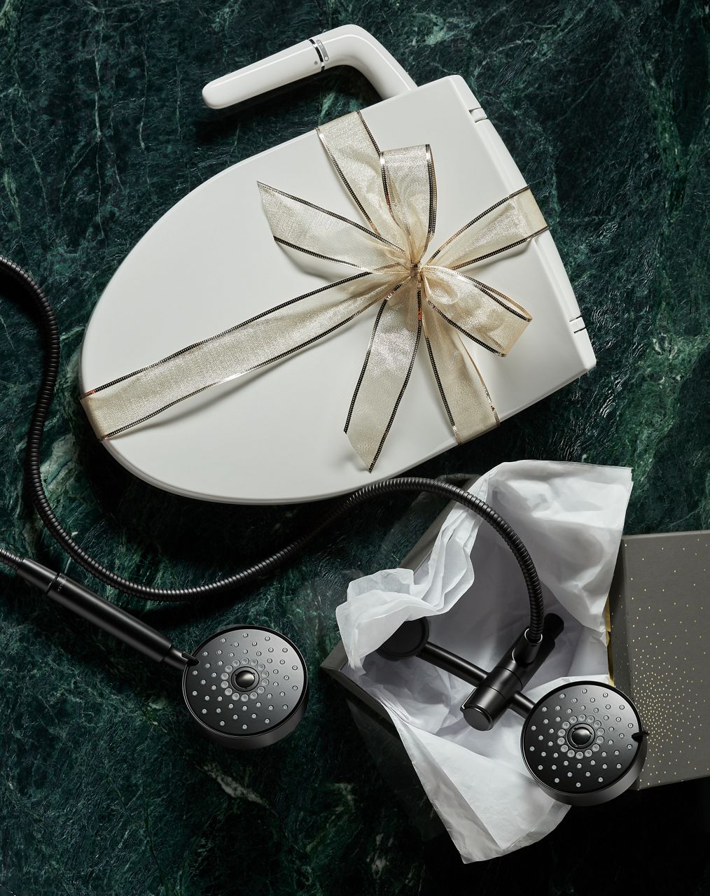 Top-down image of a table filled with holiday decor, wrapping paper, ribbons. A bidet toilet seat and showerhead are being decorated like gifts.