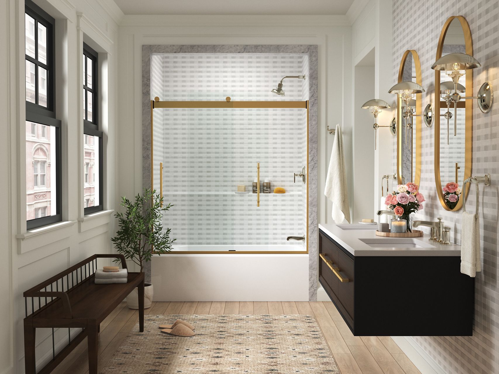 KOHLER sliding glass shower doors with gold trim at the end of a white bathroom with black wall-mounted vanity and two wall-mounted gold oval mirrors.