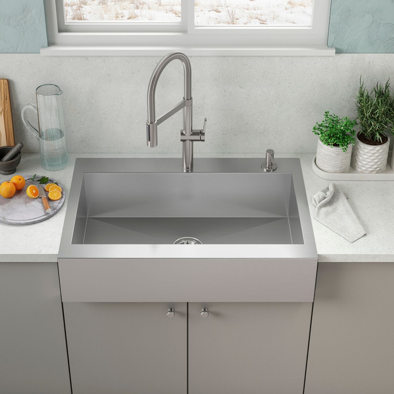 A stainless steel kitchen sink in a bright white and grey-toned kitchen.