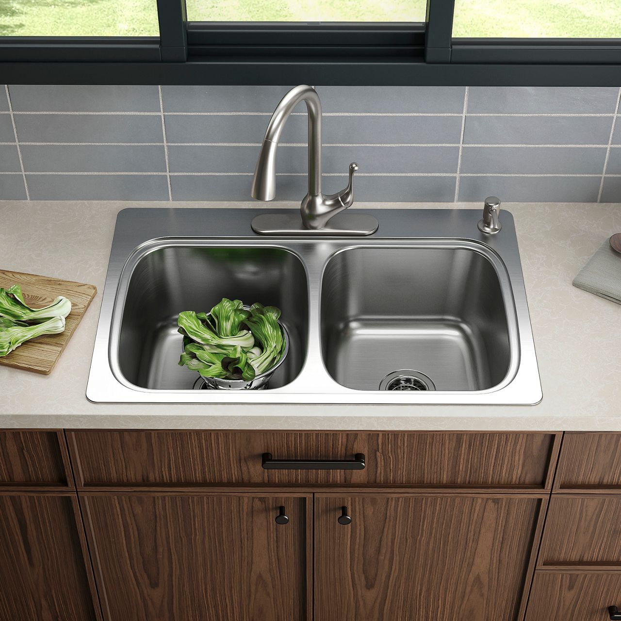Stainless steel top-mount kitchen sink alongside grey subway tile, white countertops, and dark wood cabinets.