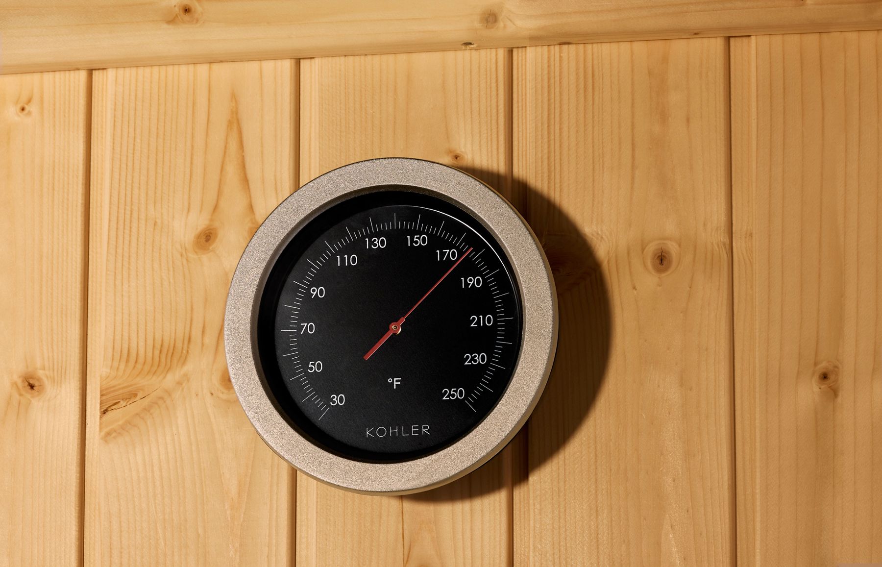 Round KOHLER sauna thermometer measuring interior heat.