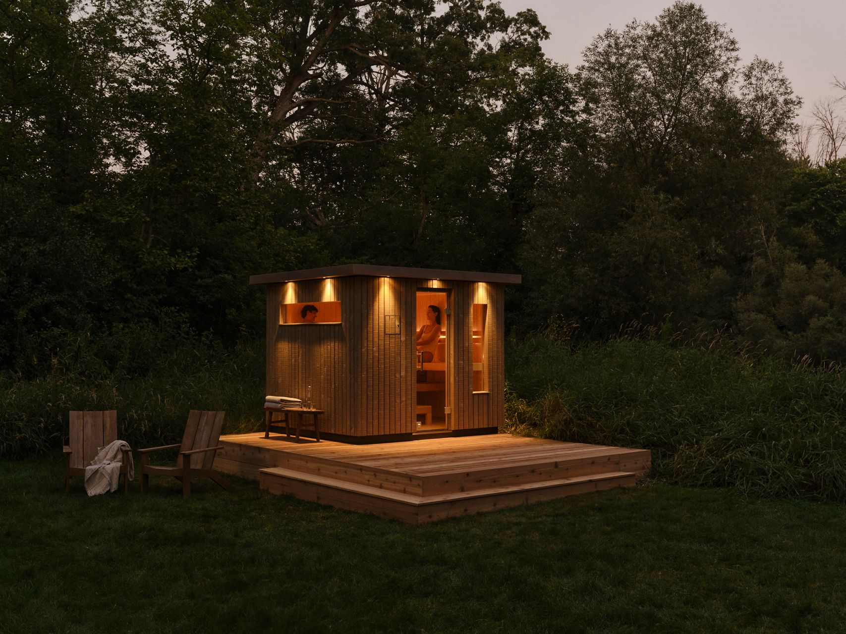 Contemporary sauna design with warm ambient lighting, wooden deck, and glass doors.