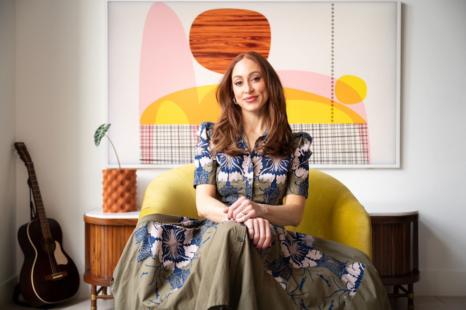 Interior designer Jess King smiling and leaning against a white painted brick wall, wearing a neutral outfit in a bright, casual portrait.
