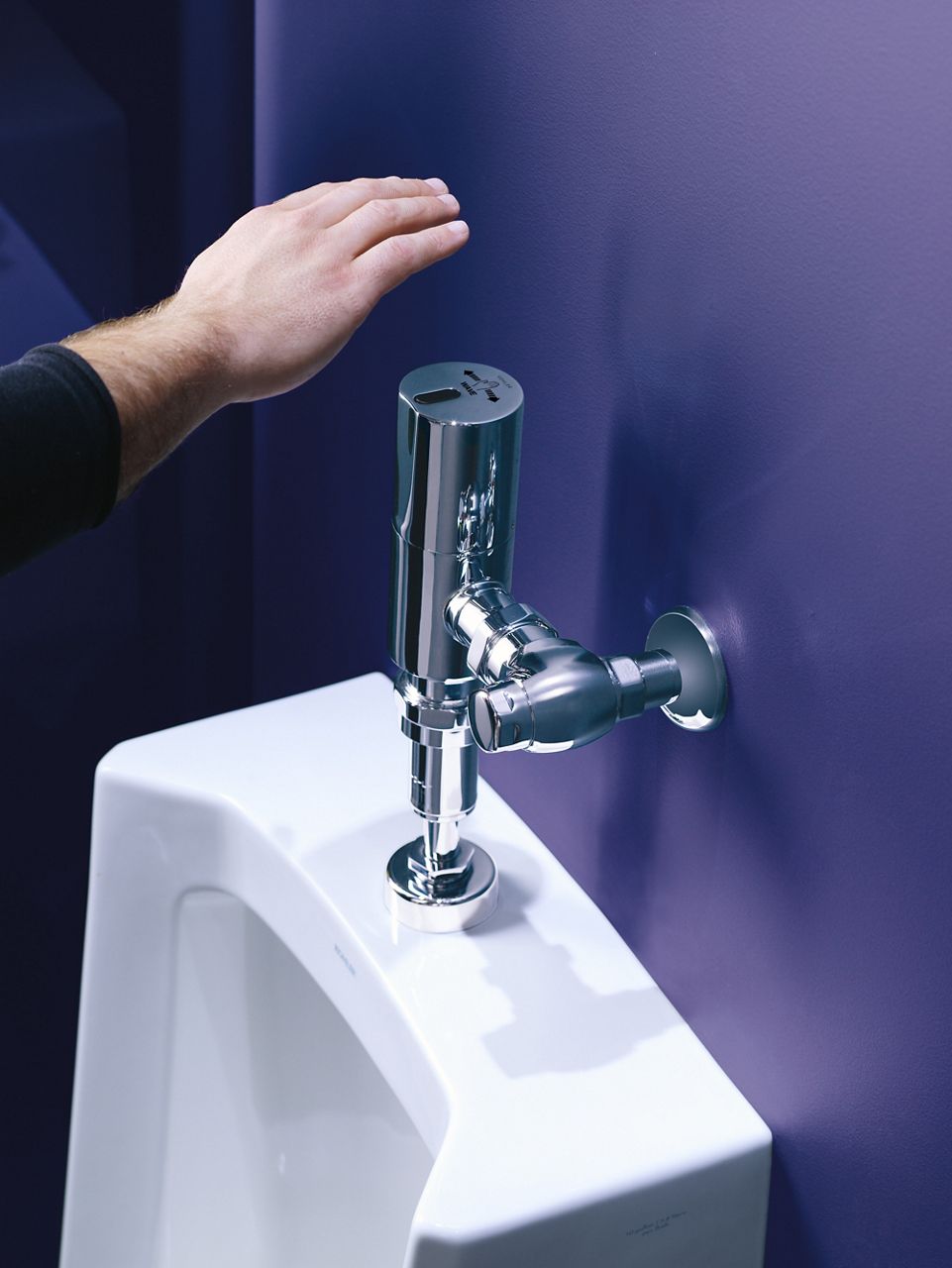 A hand passing above the touchless activation sensor of a urinal.