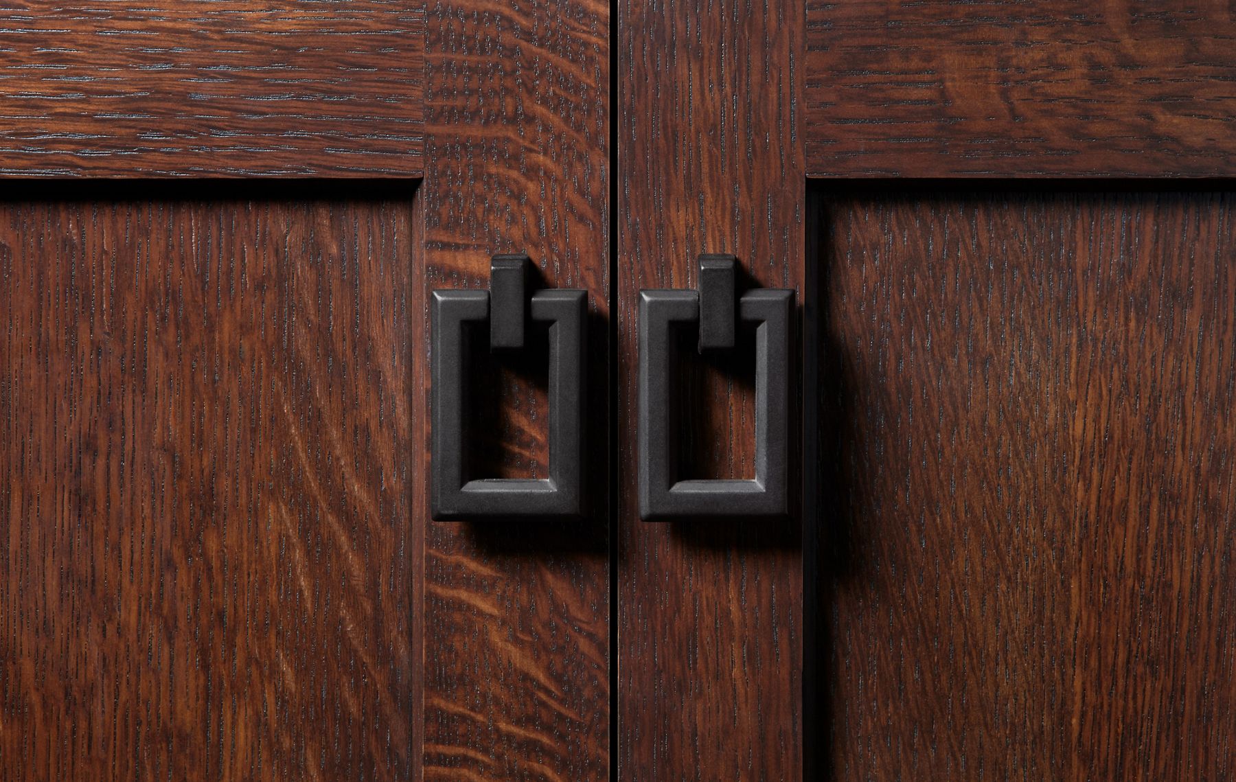 Close-up of two rectangular cabinet pulls in matte black.