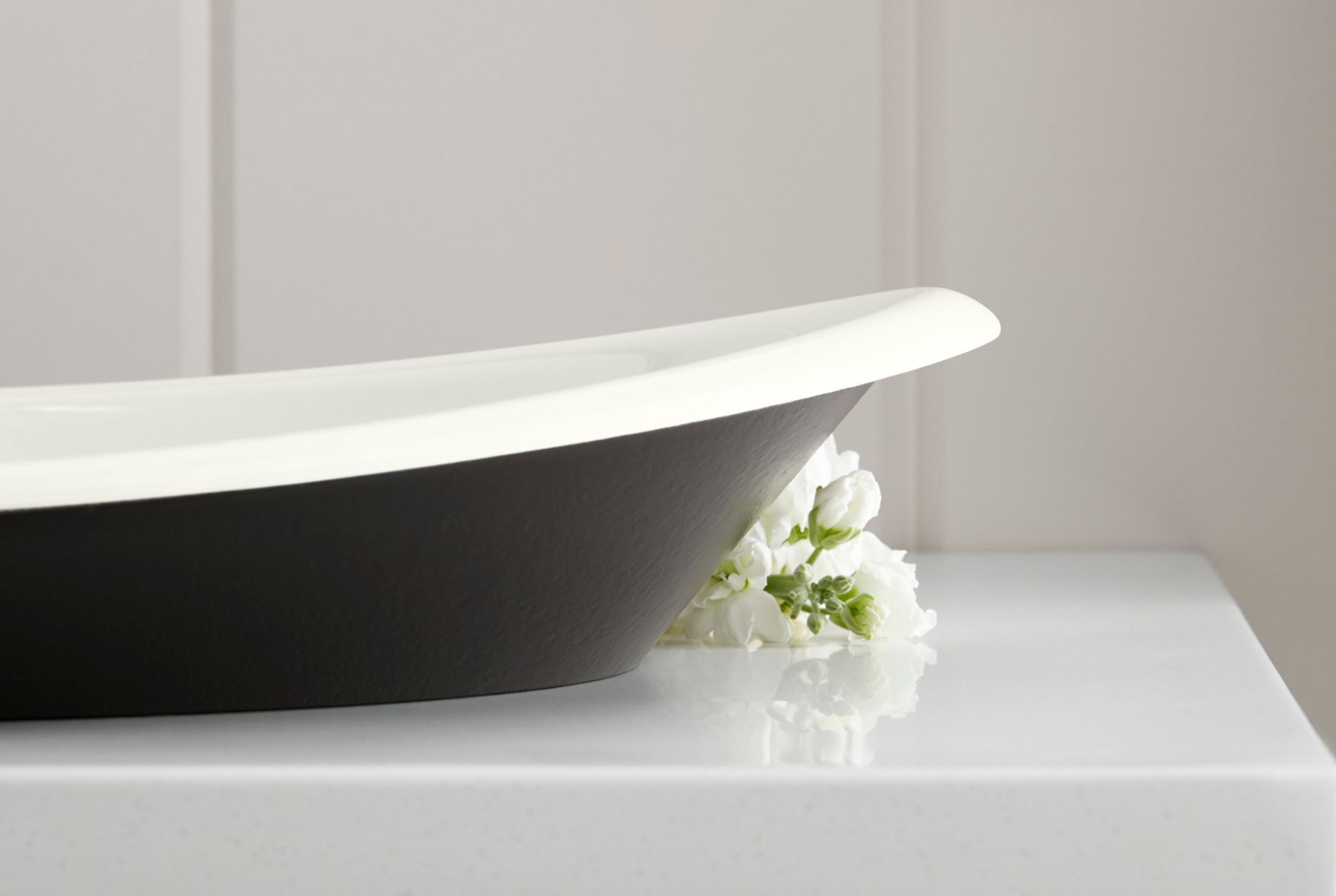 An enameled cast iron sink with a black exterior and white interior.