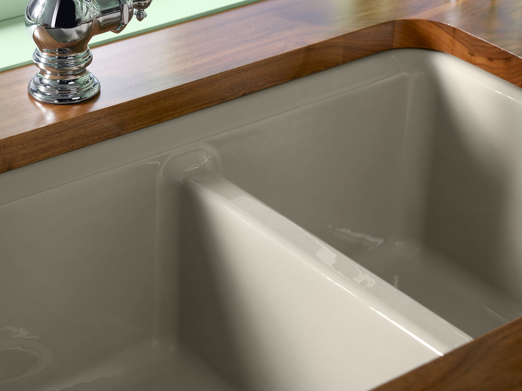 A close-up of a enameled cast iron sink with divider in the bowl.