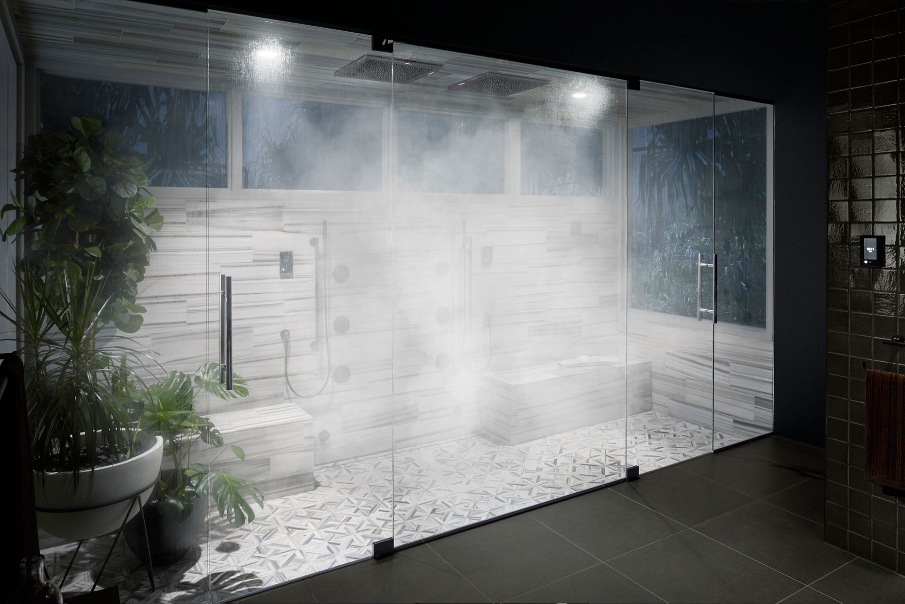 A portrait shot of a very steamy bathroom enclosed inside floor-to-ceiling screen glass doors.