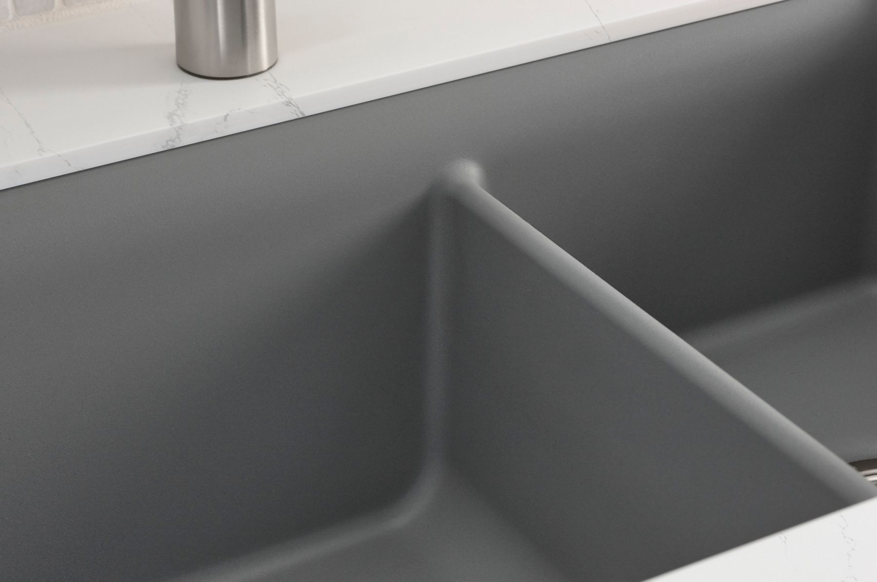 A close-up of a Neoroc sink with divider in the bowl.