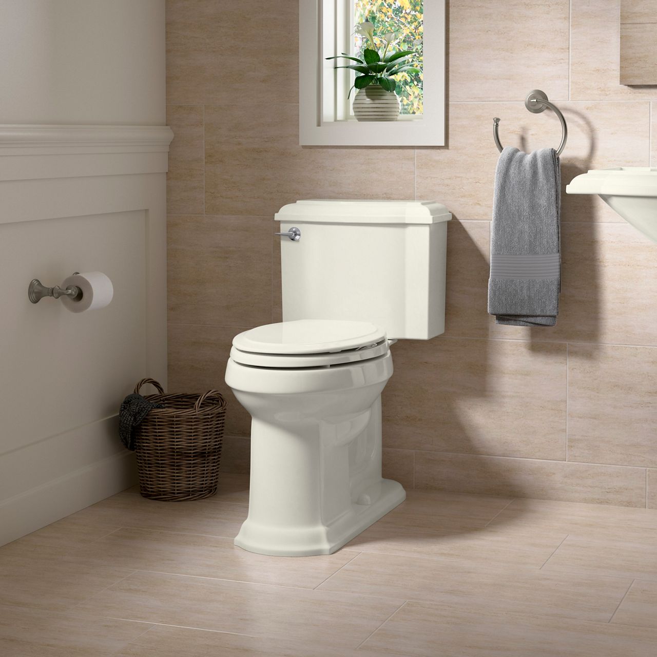 A traditional toilet in a bahtroom with beige walls and floors, and a small window above the toilet.
