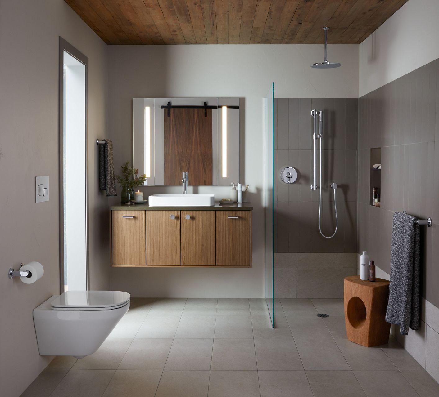 A wood-tone Jute vanity with a green top, white vessel sink, polished brass hardware and faucet, and a lighted mirror with side panels.