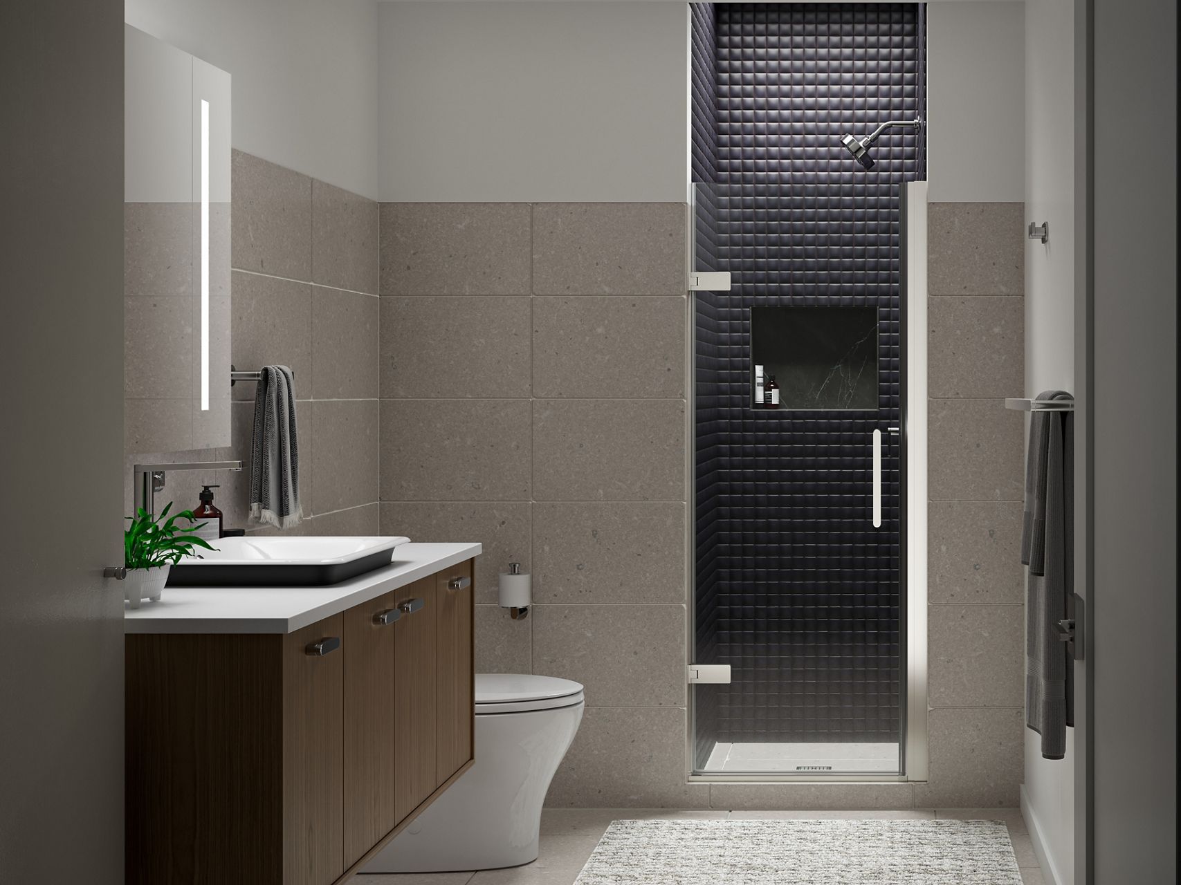 Dark gray tiled shower with KOHLER glass pivot shower door at the end of a bathroom with white and beige walls and brown wall-mounted vanity.