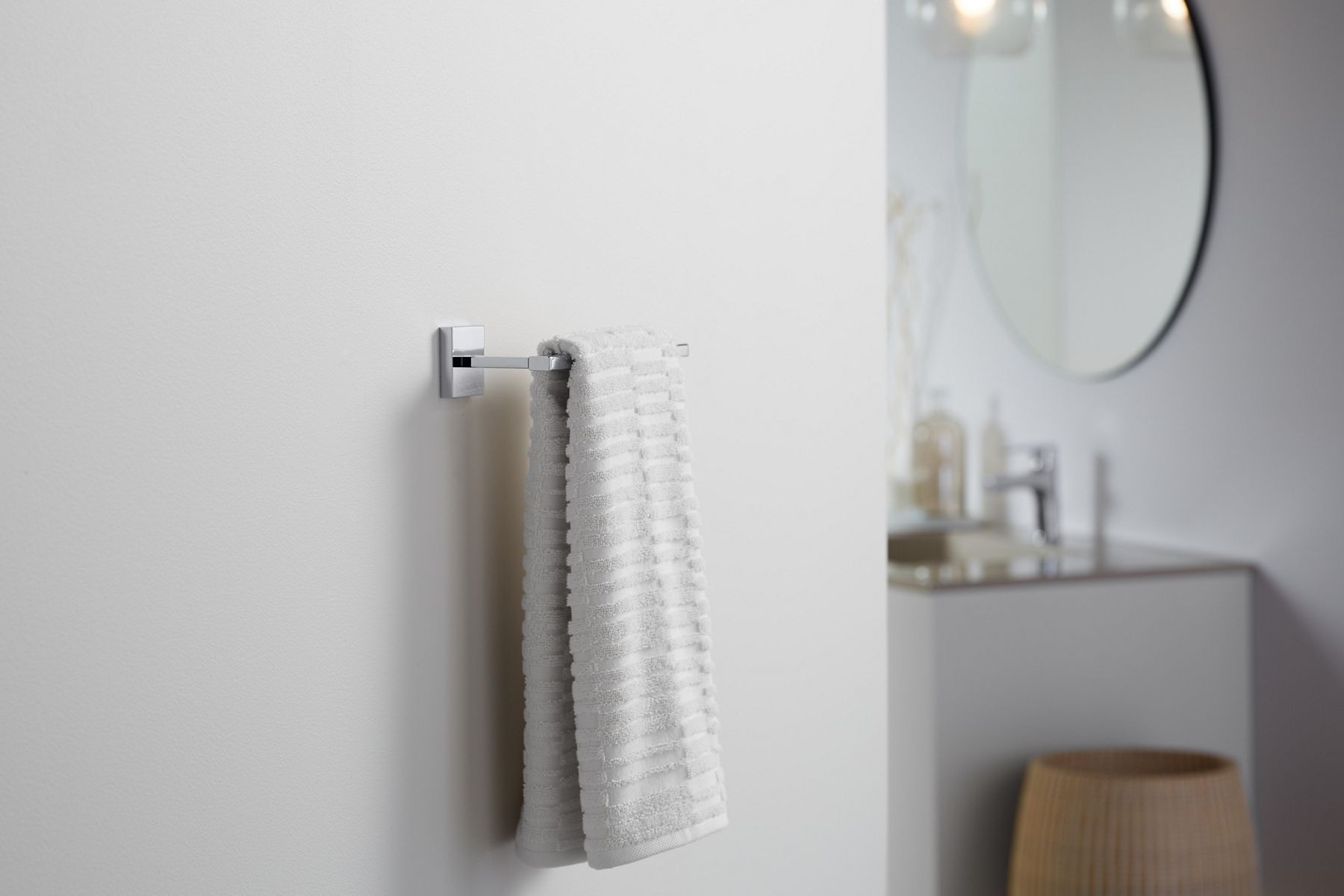 A bath towel hanging from a towel bar on a white wall.