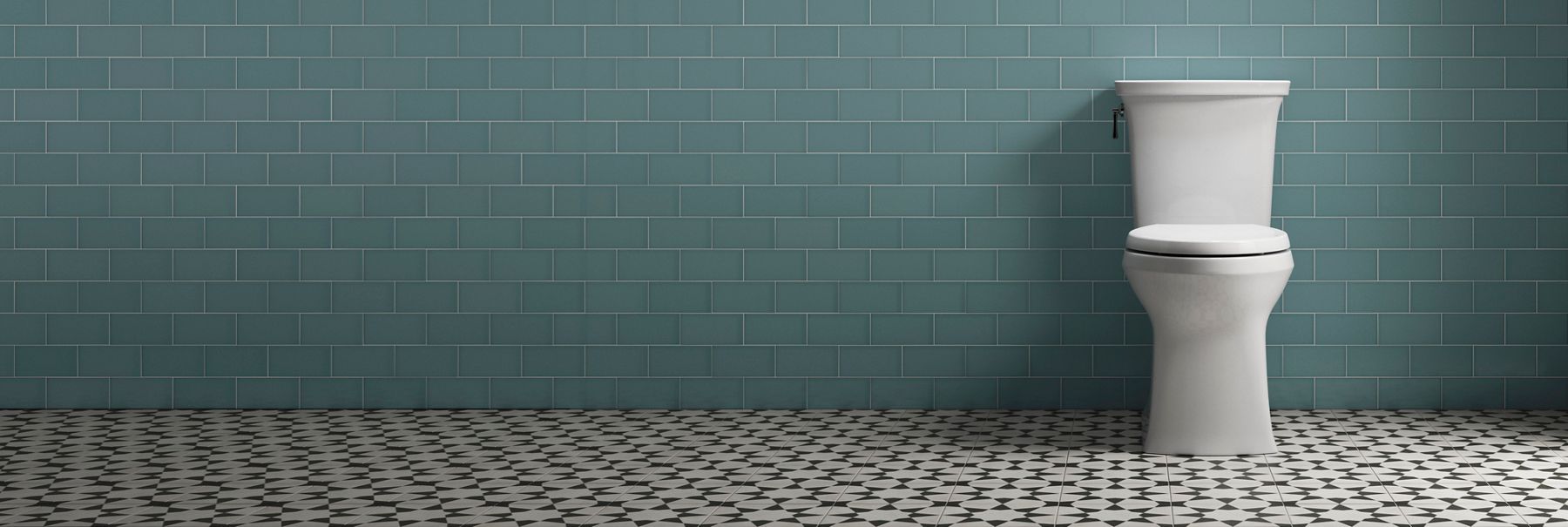 Toilette jupée Kohler devant un mur en carrelage vert
