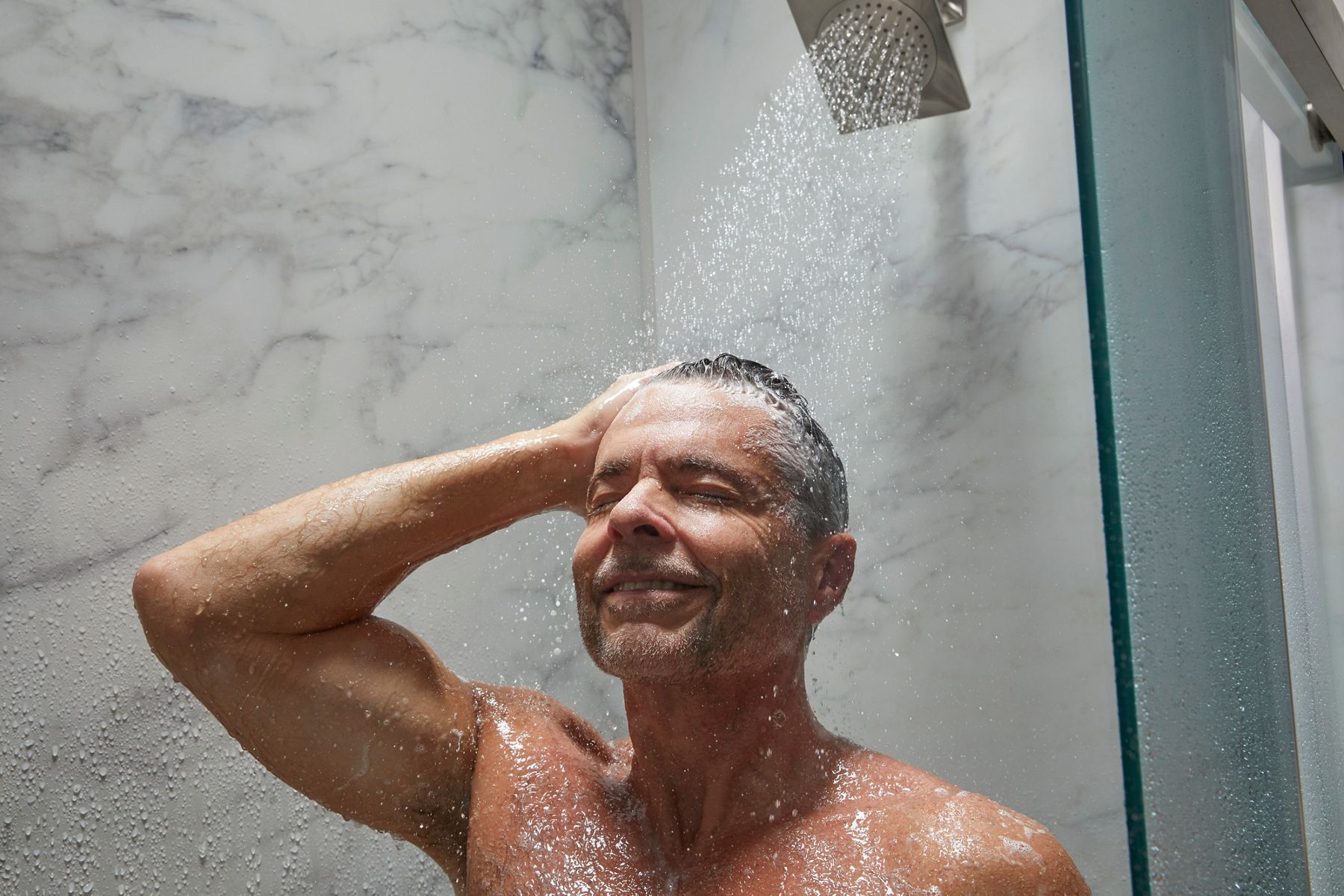 man washing shampoo out of hair