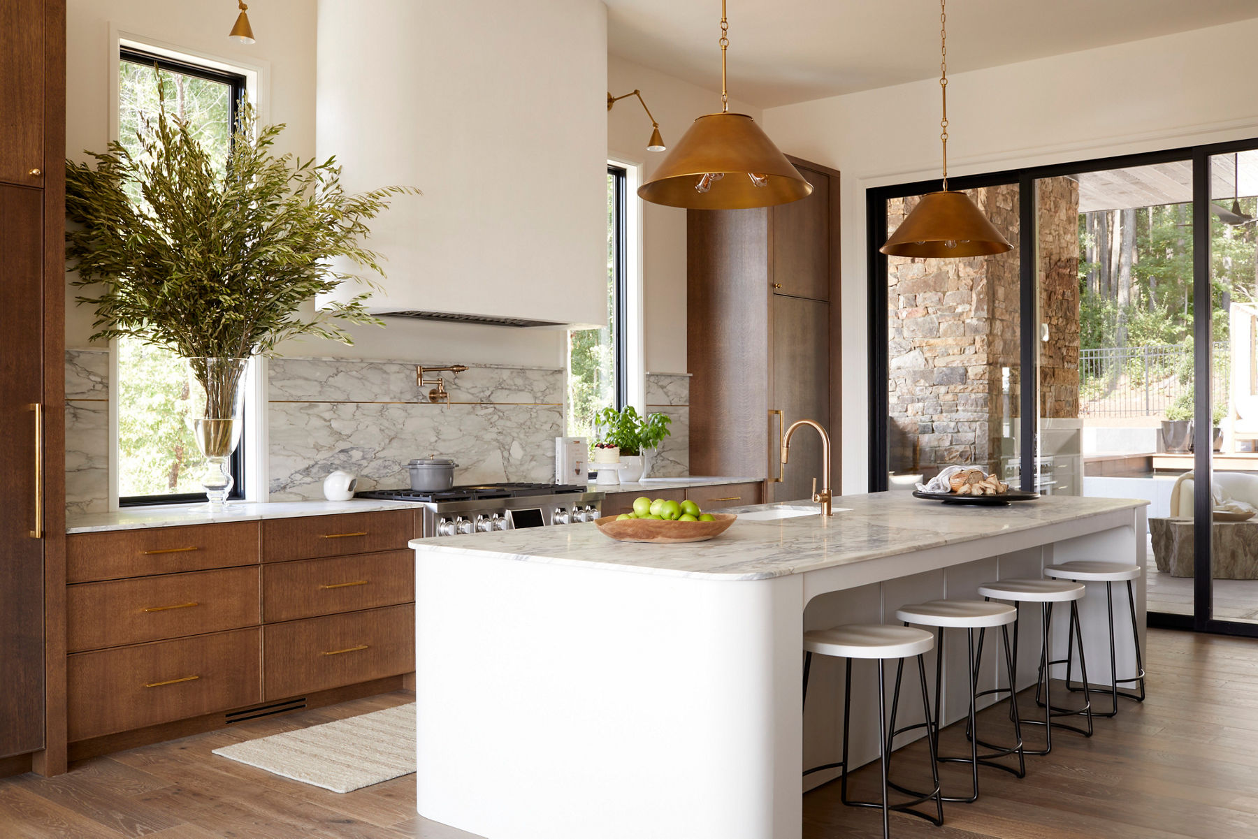Modern kitchen with luxurious stone slab countertops, spacious island seating, and pendant lighting complemented by warm wood cabinetry