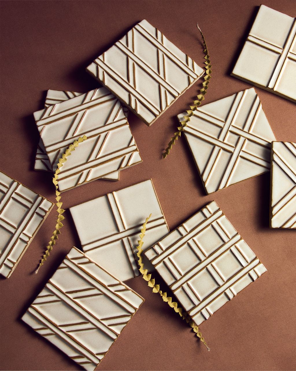 Glazed ceramic tile assortment featuring raised geometric linework patterns in a soft ivory finish