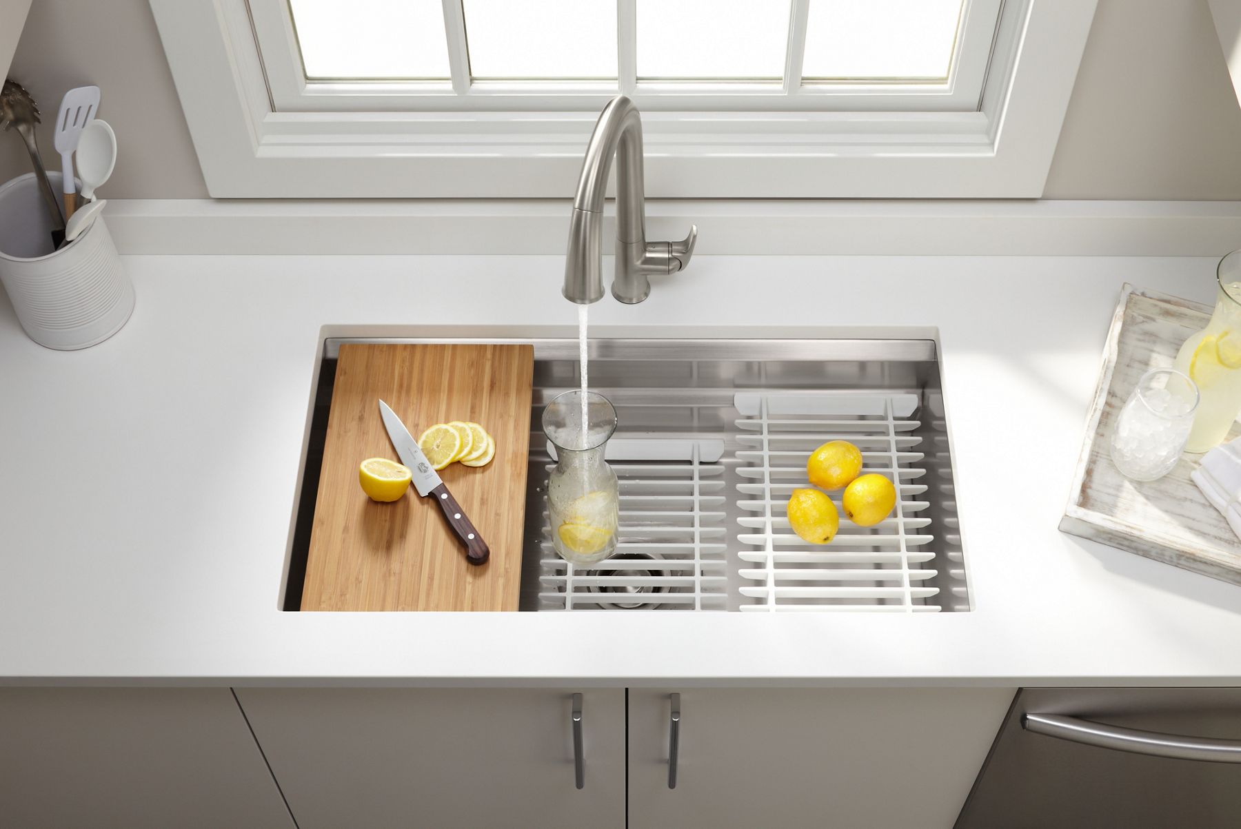 Overhead view of KOHLER sink with faucet, bamboo cutting board, and racks