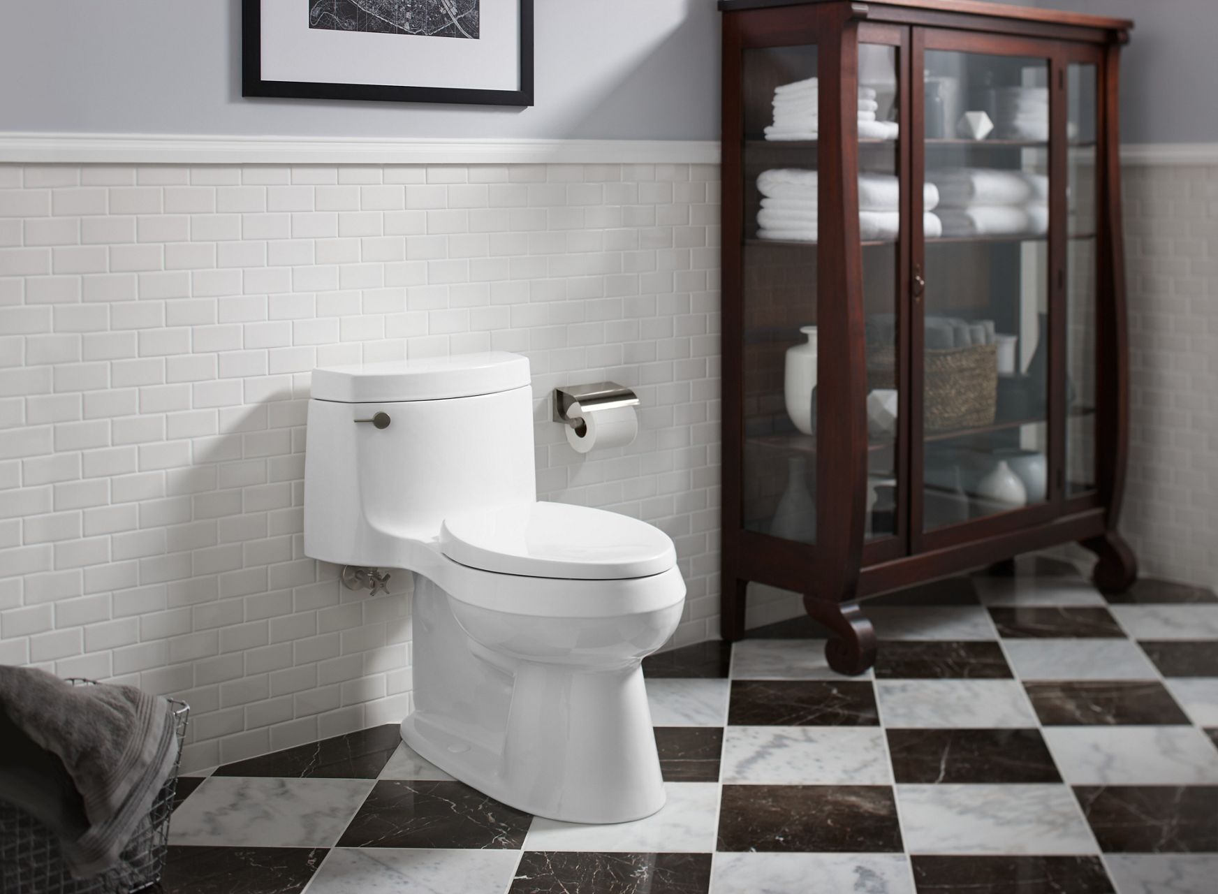 KOHLER toilet in high contrast bathroom with storage cabinet