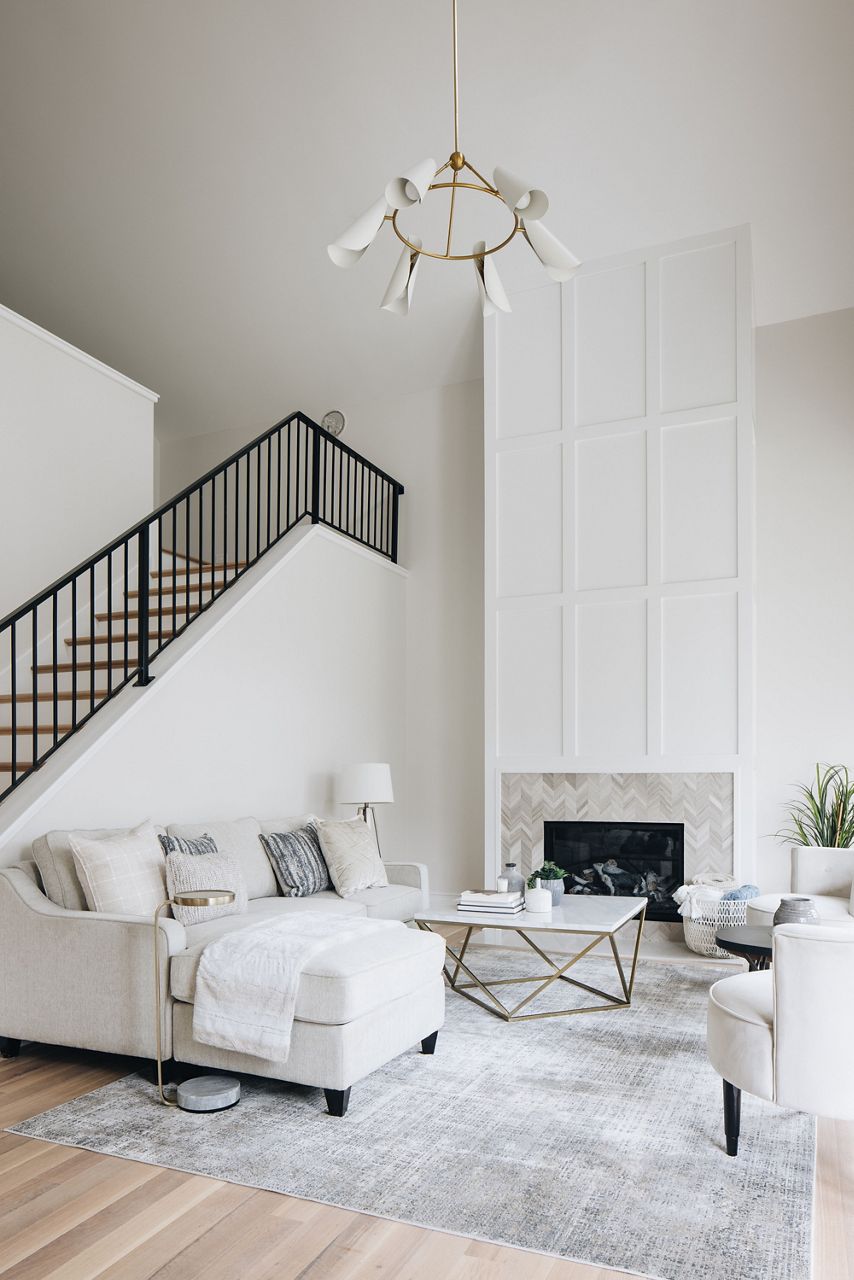 A white living room with a fireplace and stairway leading to a second floor.