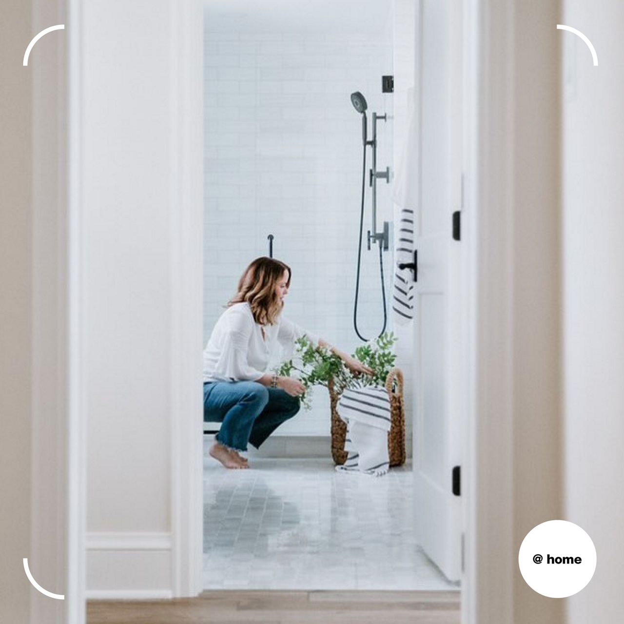 A woman tends to a plant in a bathroom with KOHLER shower kit