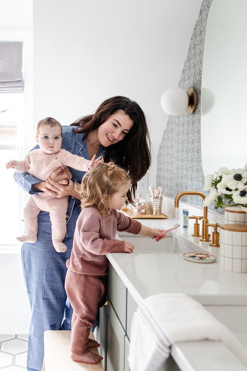 Image of Elizabeth Rees, featured influencer and co-founder of the wallpaper design company Chasing Paper, smiling at the counter of her bathroom sink with her two children, washing their hands.