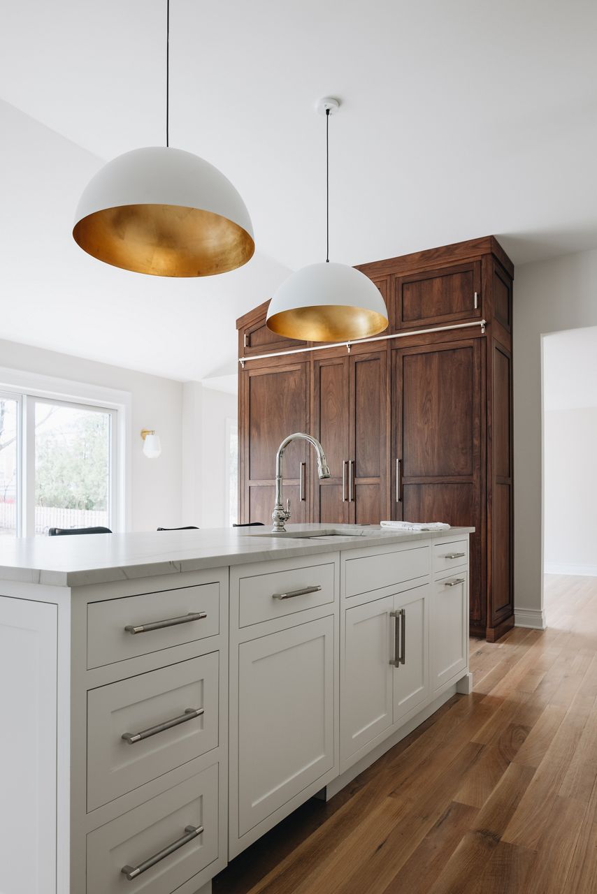 A large island with white top and white cabinets, KOHLER Prolific sink, and Artifacts single-hole touchless faucet.