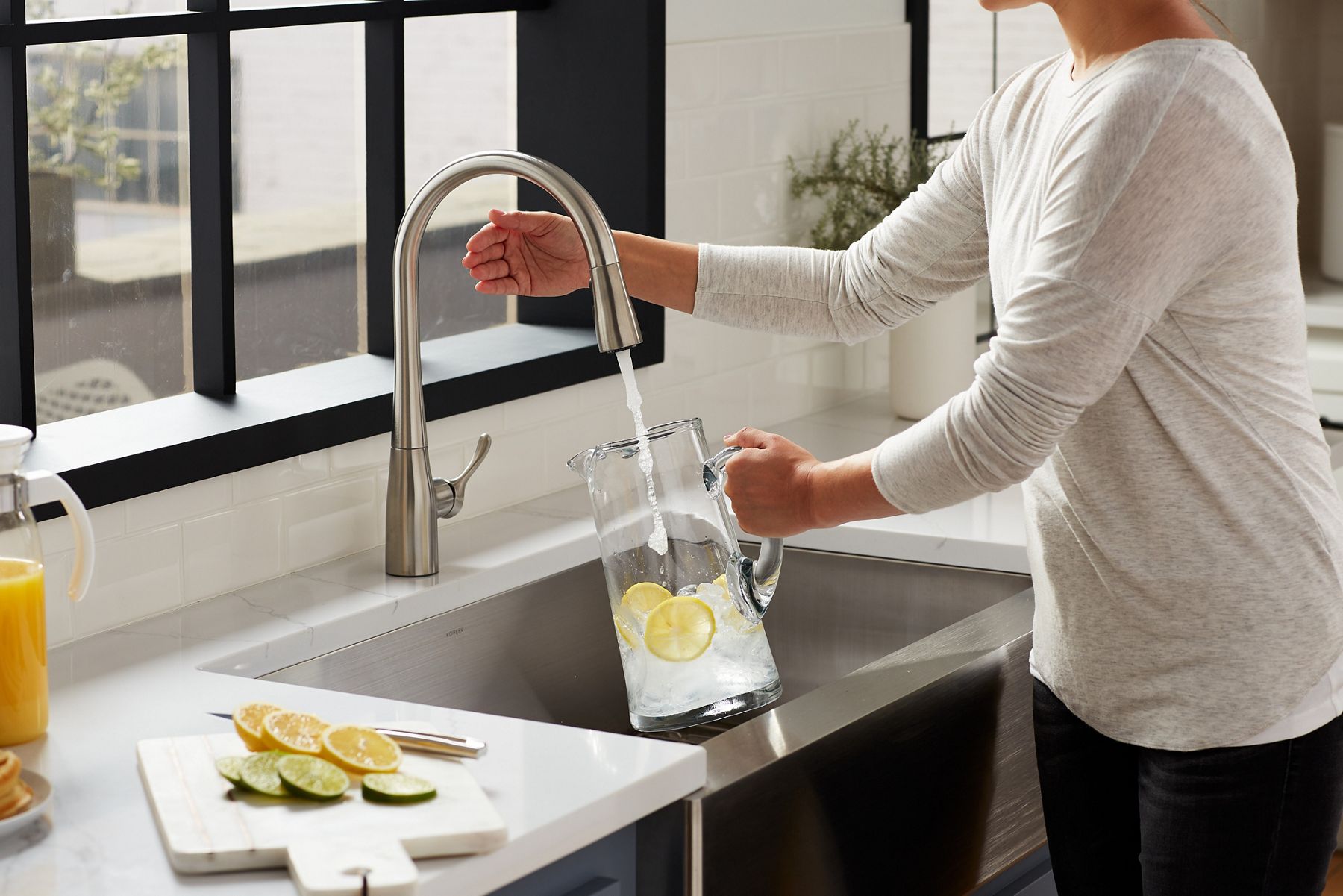 Une personne remplit un pichet d’eau d’un robinet d’évier de cuisine KOHLER