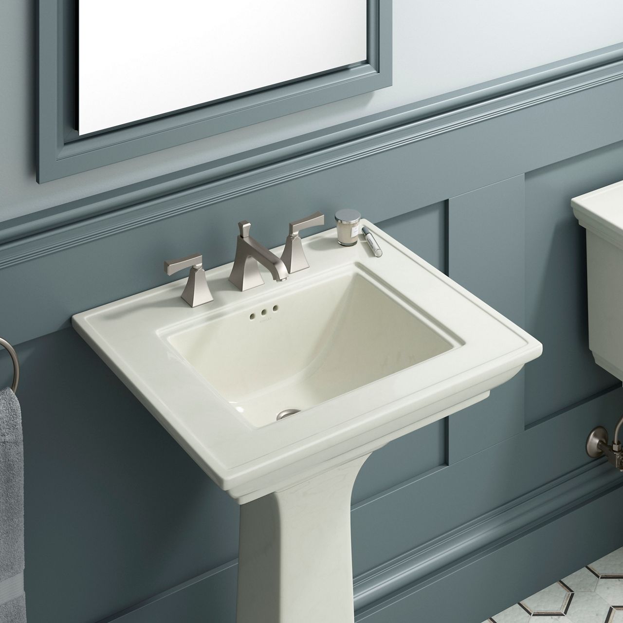 A pedestal sink in off-white against a grayish blue paneled wall.