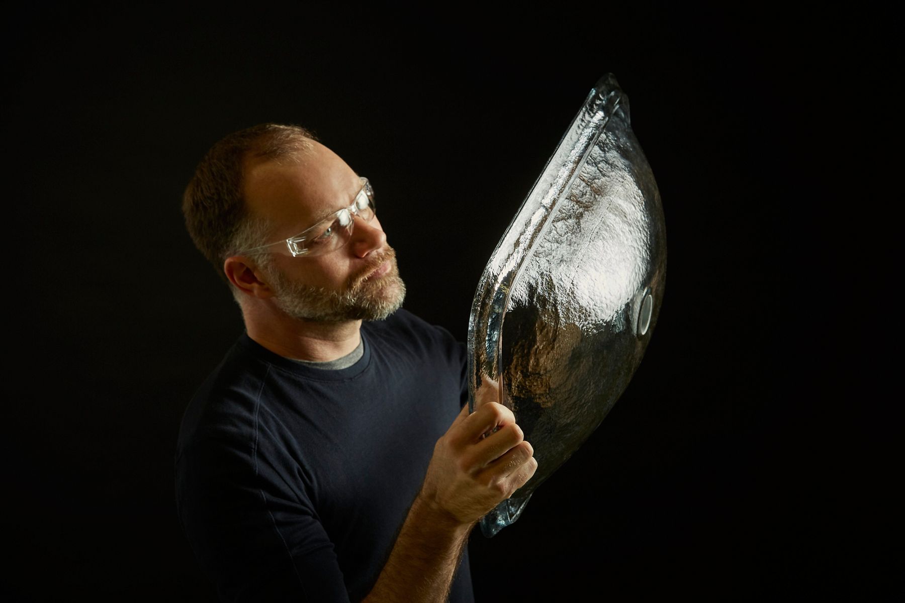 An artist examining a glass sink prototype