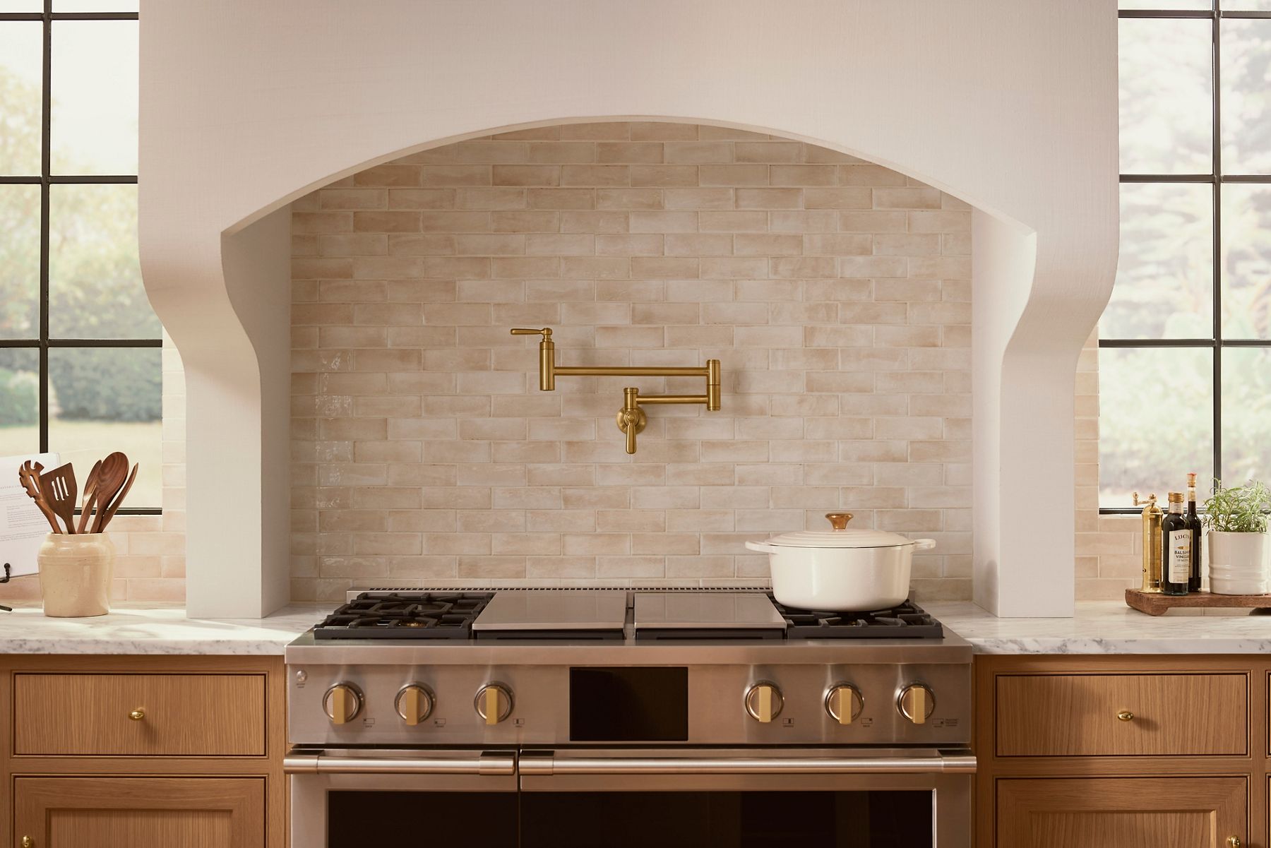 A range top with a brushed brass pot filler designed by Shea McGee.