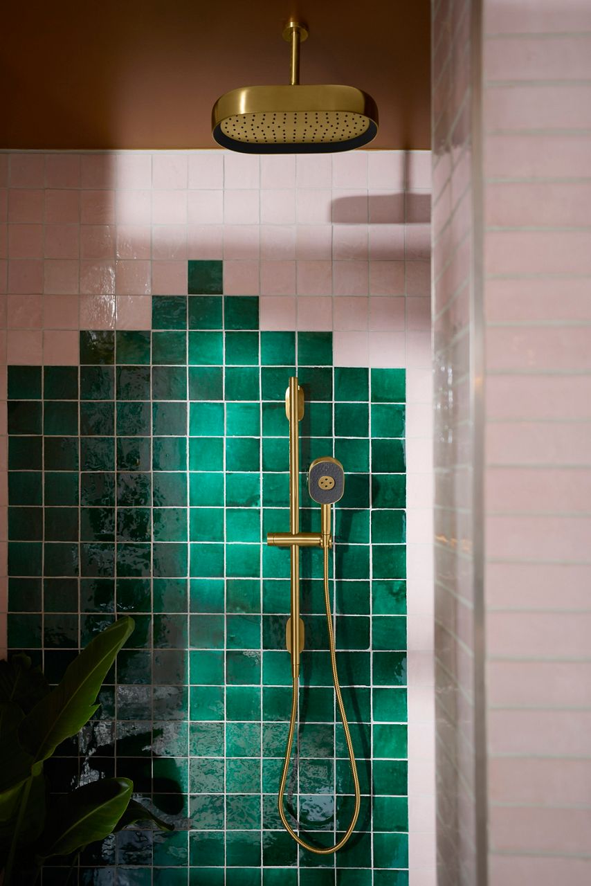 Image of the showering area in bathroom designed by Justina Blakeney for Kohler's Heritage Color collection. Image focuses on the Statement showering fixtures in brass finish, installed against colorful tile shower walls.