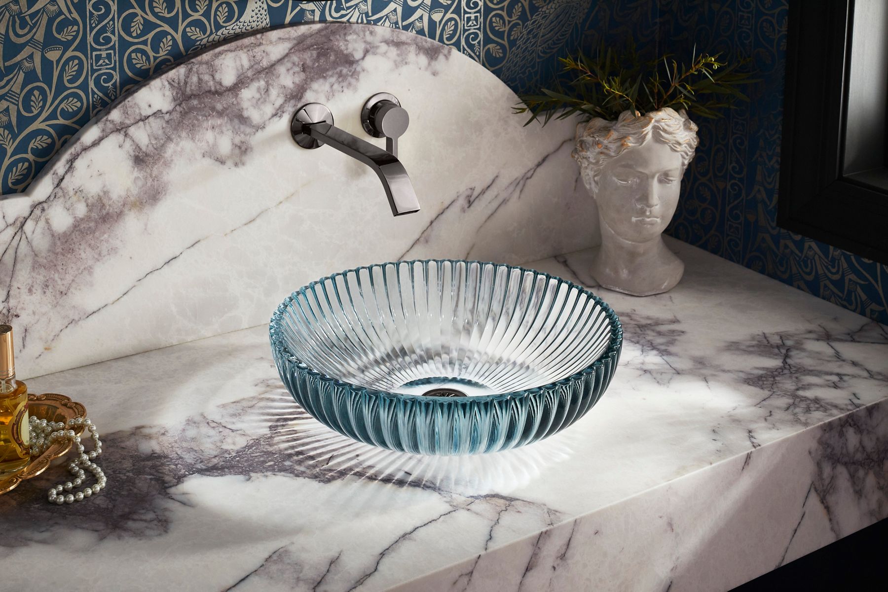 Modern bathroom featuring a clear glass Kohler vessel sink paired with chrome wall-mounted faucet; 