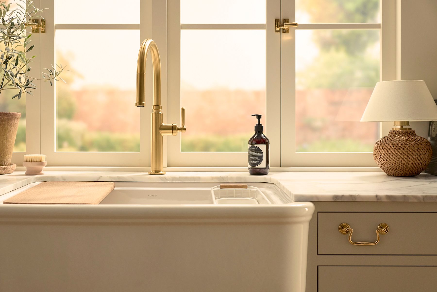 Farmhouse sink with apron front and tall gooseneck faucet beneath a window.