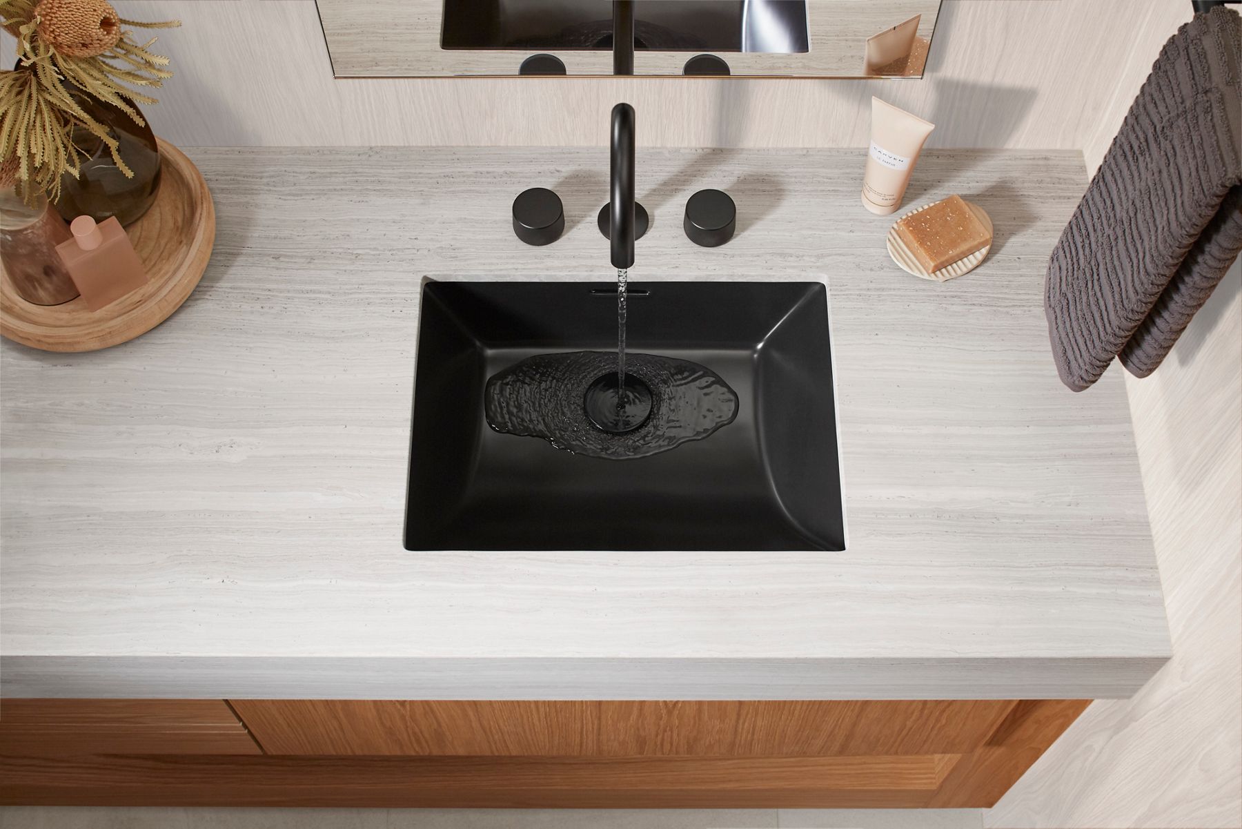 Close up of water pouring into a matte black sink.