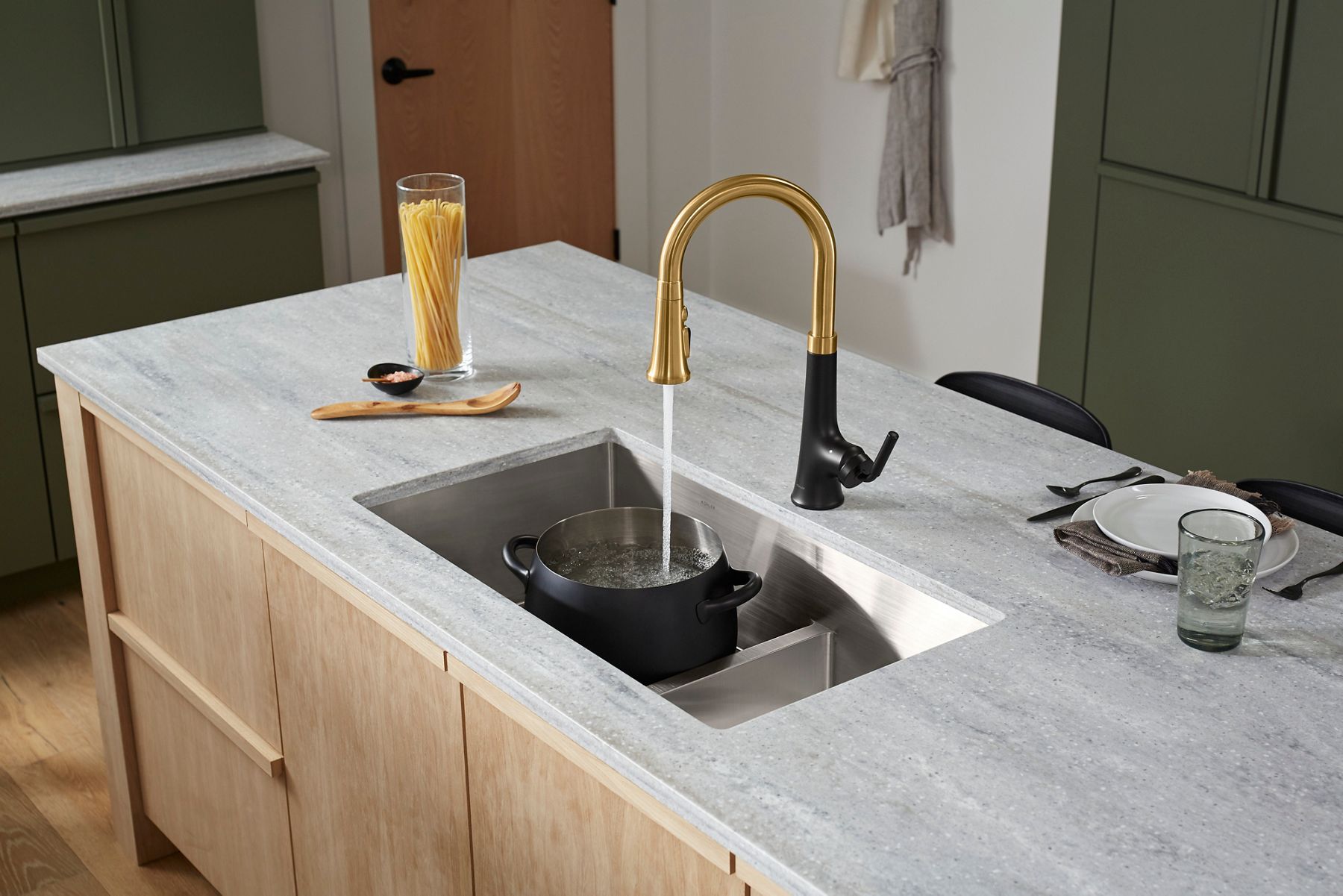 Kitchen island with an undermount sink, two-tone faucet, and light gray countertop in a contemporary kitchen.