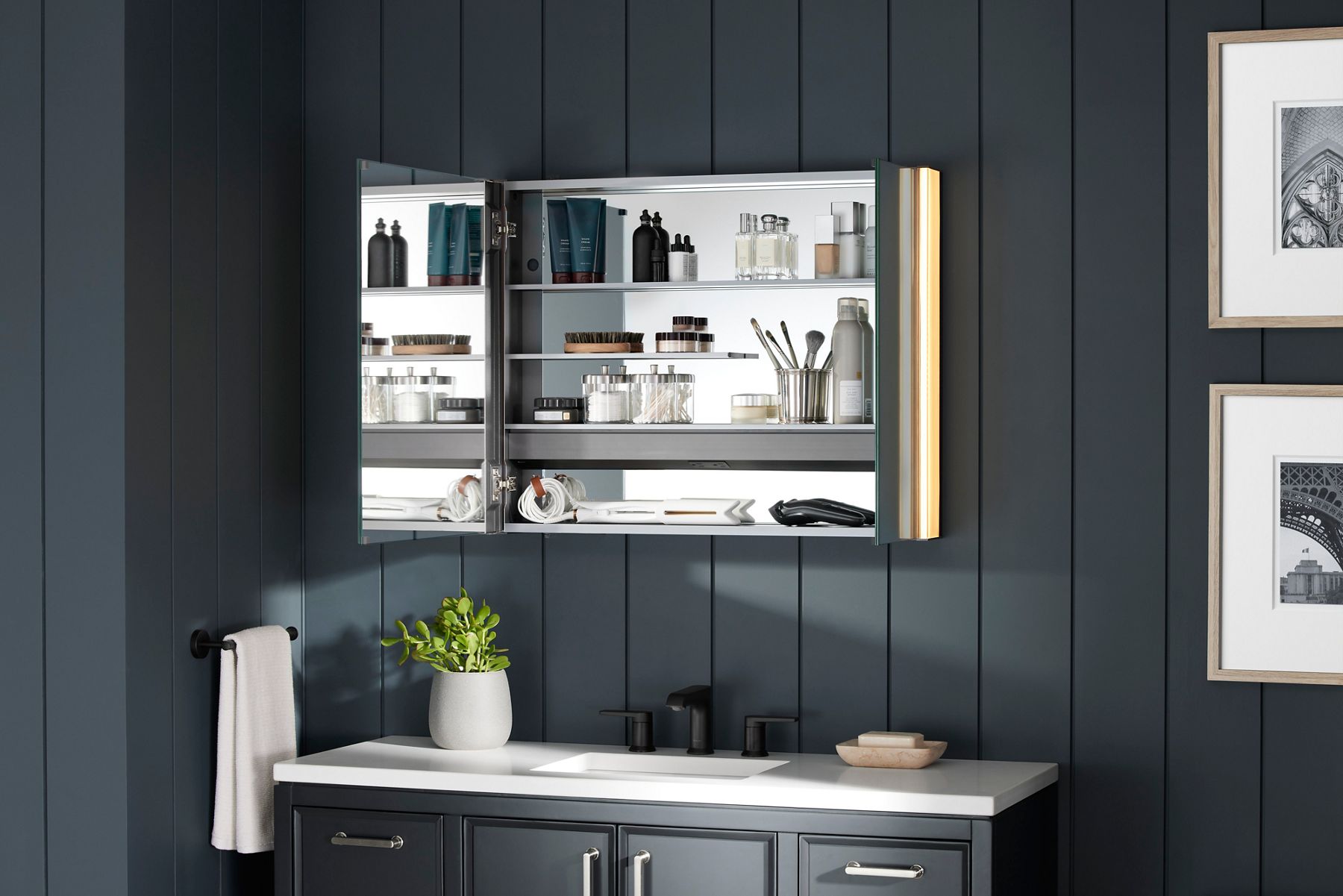 A bathroom styling space with bluish gray walls a matching vanity, and a medicine cabinet with the door open.