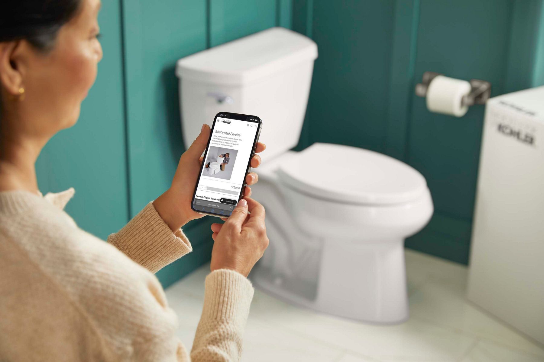A women on her phone looking at pricing for install services and a white toilet in the background.