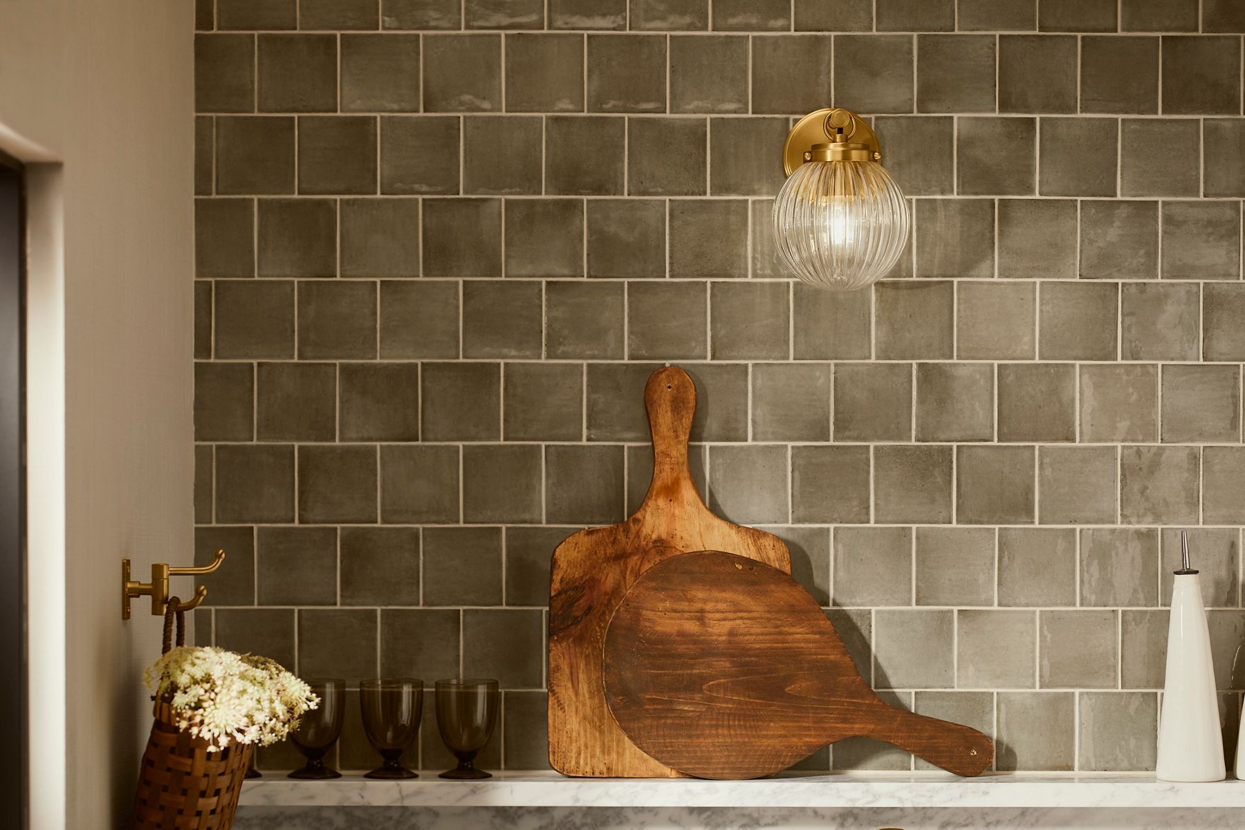 Grayish green square wall tile with irregular surfaces and slightly different colorations to lead a sense of texture to the wall.