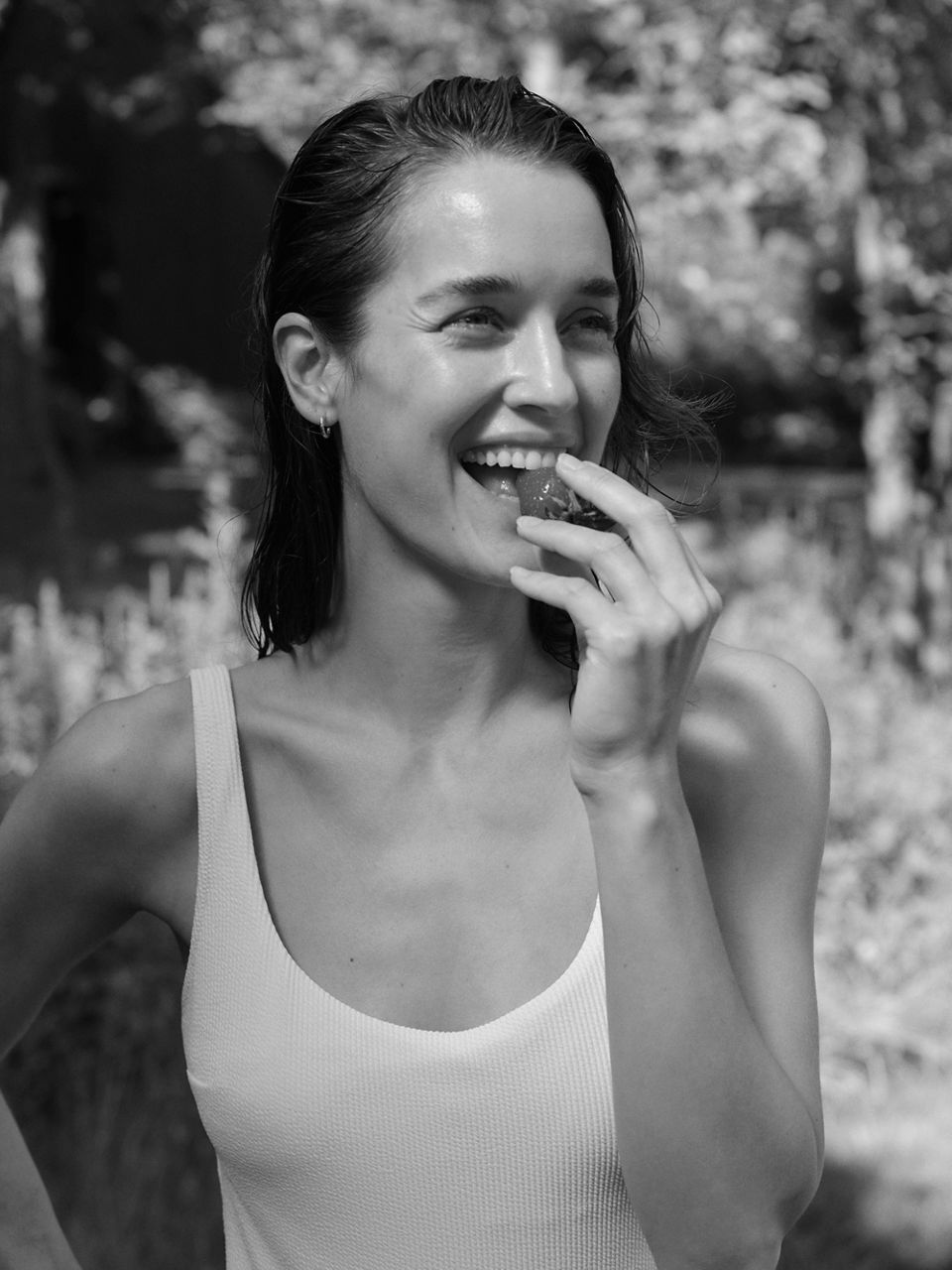 A woman smiling and biting into a strawberry.