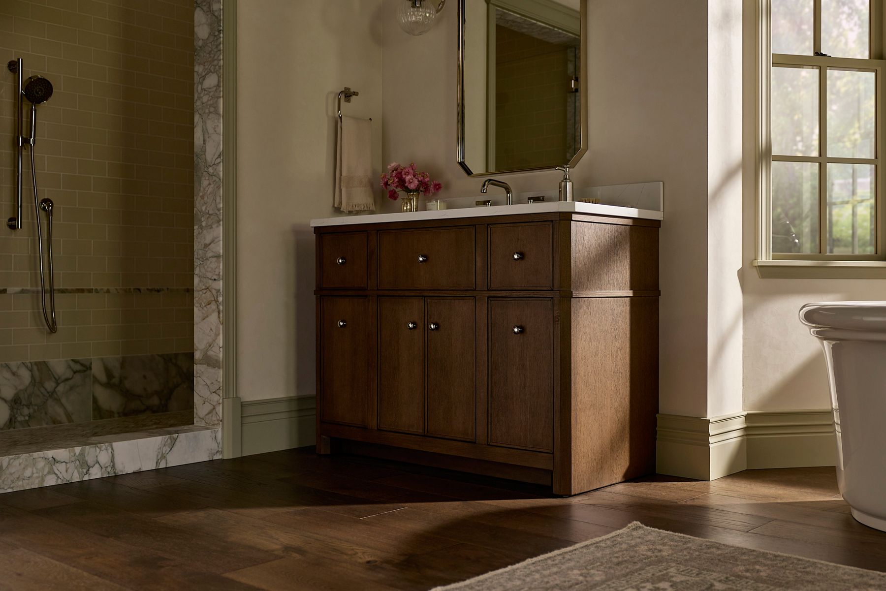 Claude vanity with matching mirror and Castia sink faucet in a silver-tone finish in a warm, neutral bathroom with natural light from windows.
