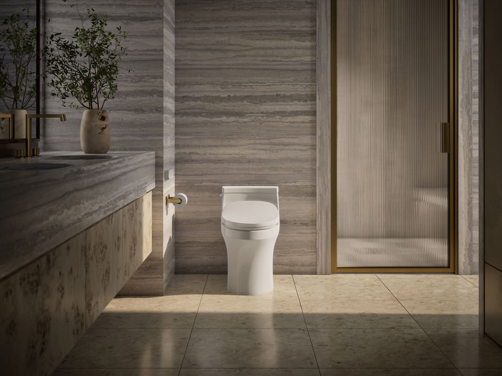A streamlined white toilet with an integrated bidet toilet seat in a neutral bathroom with gold fixtures.