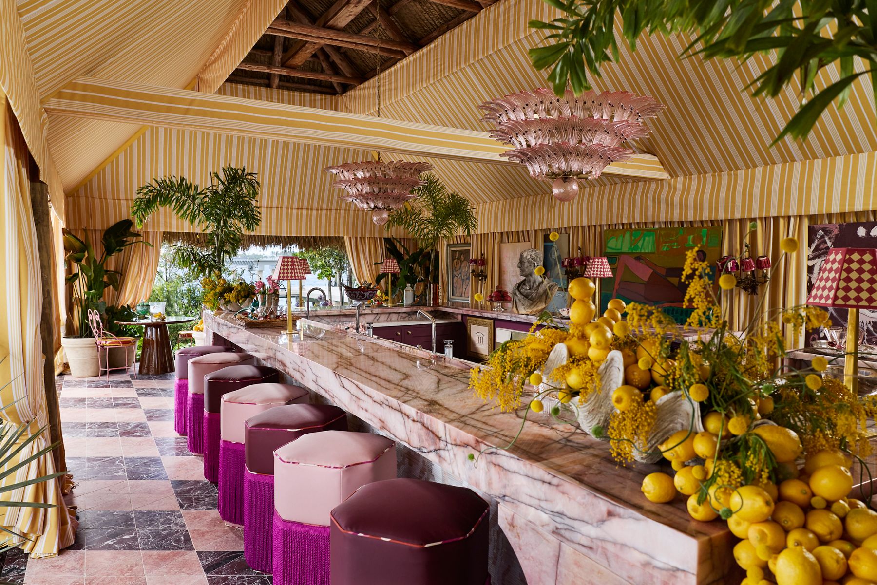 A large, colorful cabana-inspired space featuring an expansive pink stone bar and tropical decor.